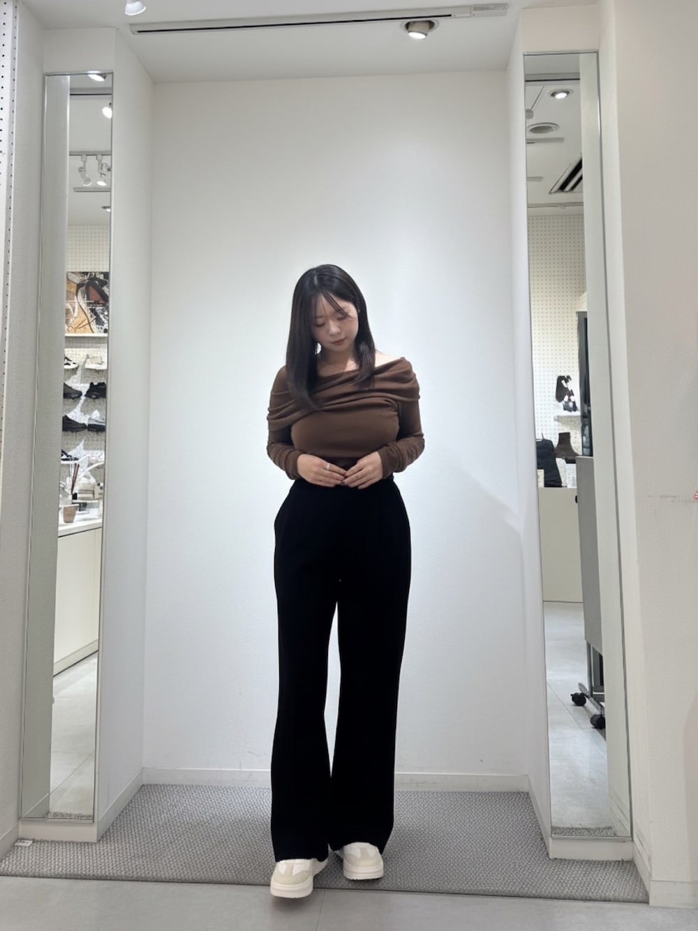 ベージュ系のスニーカー、ブラウン系のトップス、ブラック系のスラックスを着用したレディースの冬コーディネートの1枚目の写真