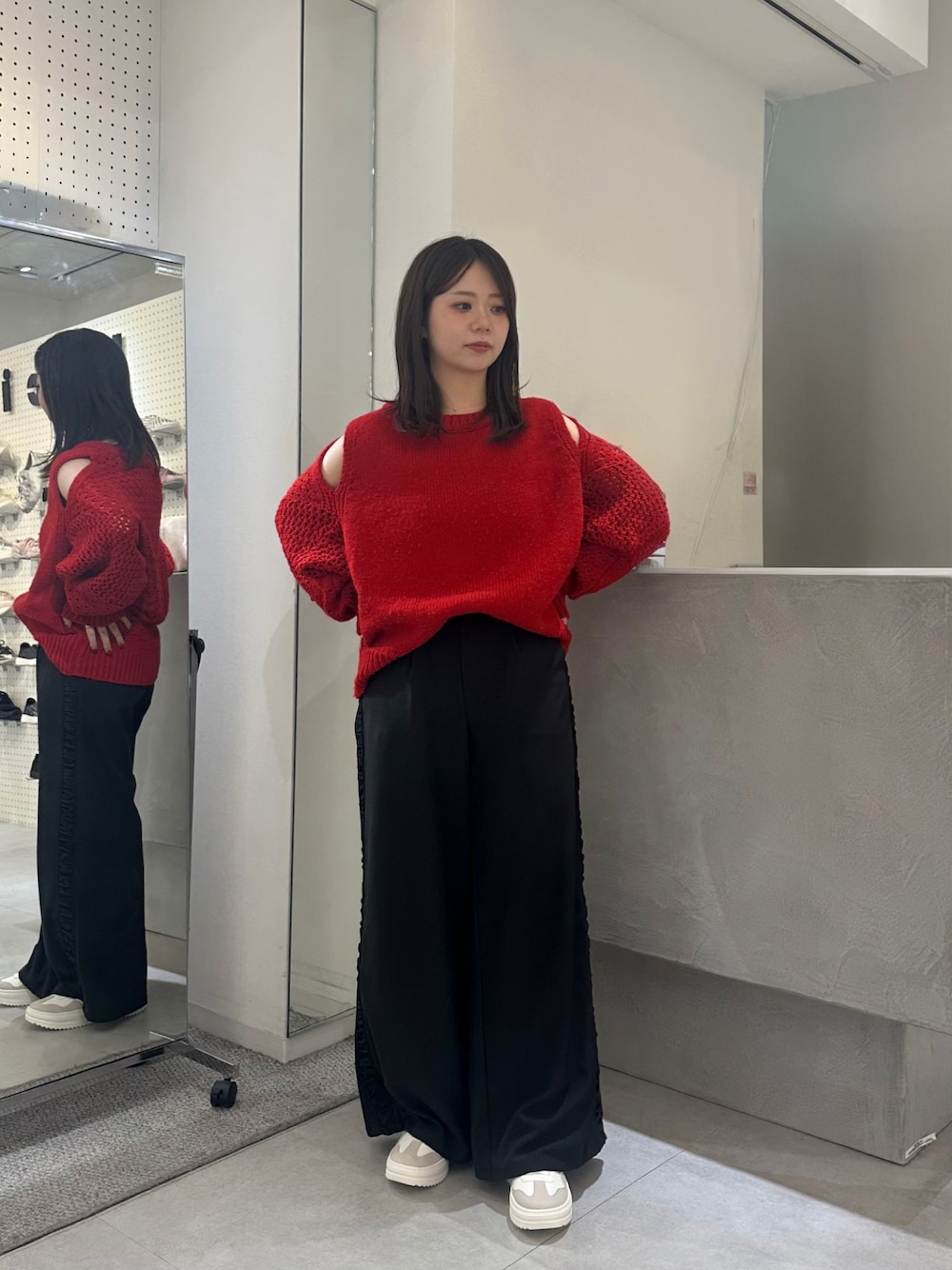 ブラック系のスラックス、ブラウン系のスニーカー、レッド系のニット/セーターを着用したレディースの秋コーディネートの1枚目の写真