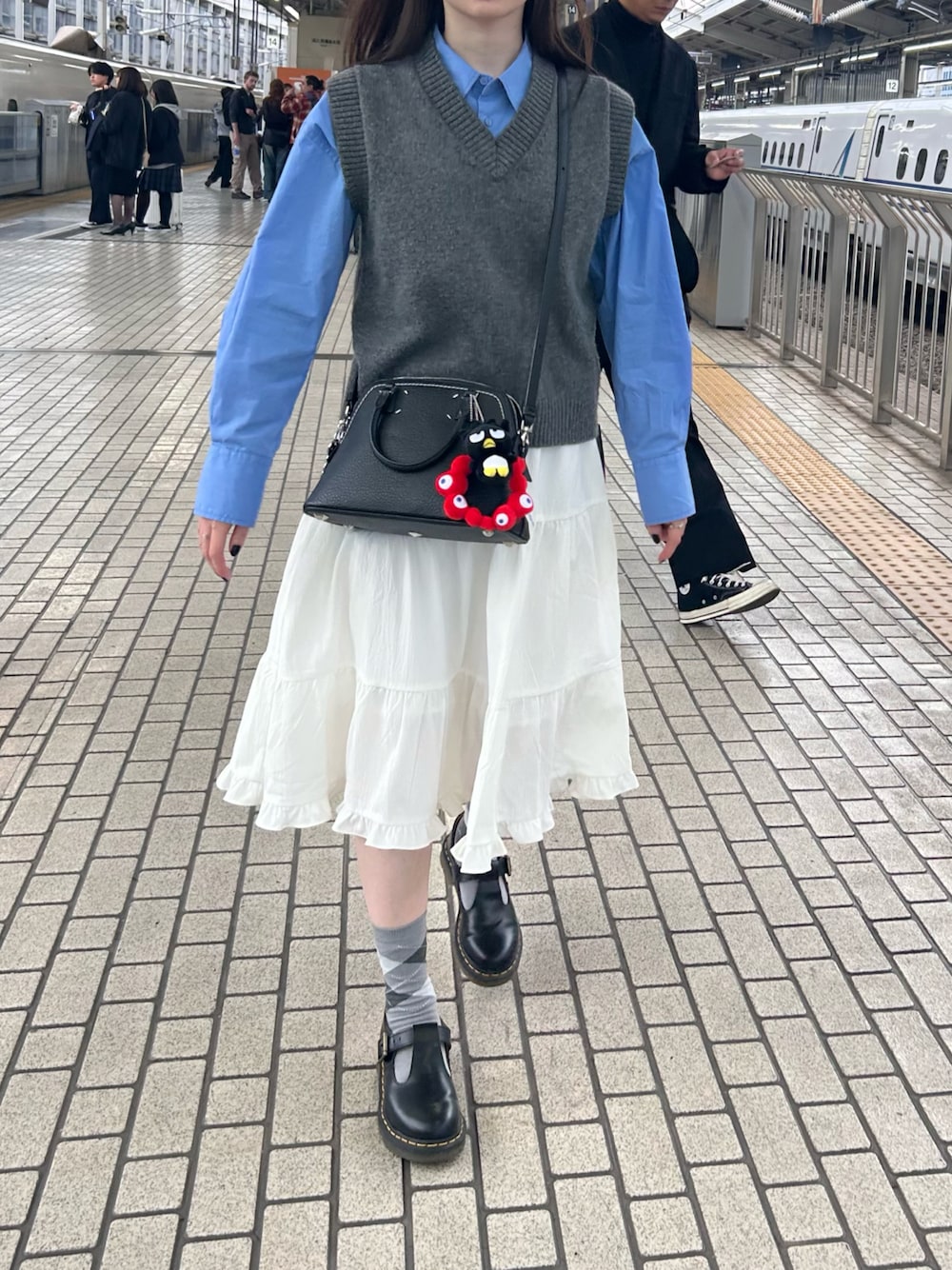 ホワイト系のスカート、グレー系のベスト、ブルー系のシャツ/ブラウスを着用したレディースの秋コーディネートの1枚目の写真