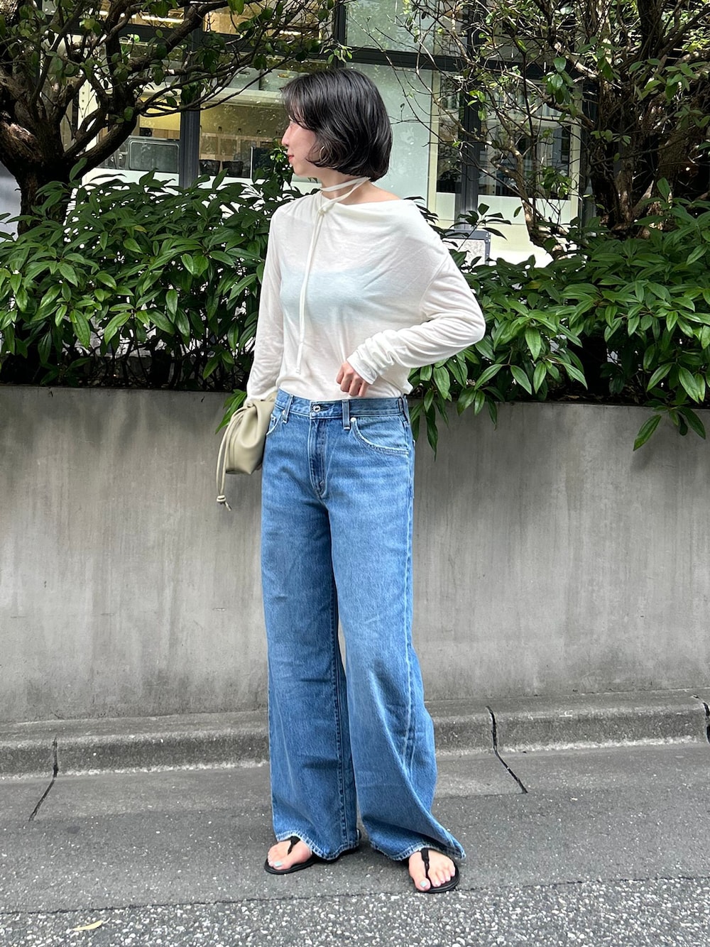 ブルー系のデニムパンツ、ホワイト系のTシャツ/カットソー、ベージュ系のクラッチバッグを着用したレディースの夏コーディネートの1枚目の写真