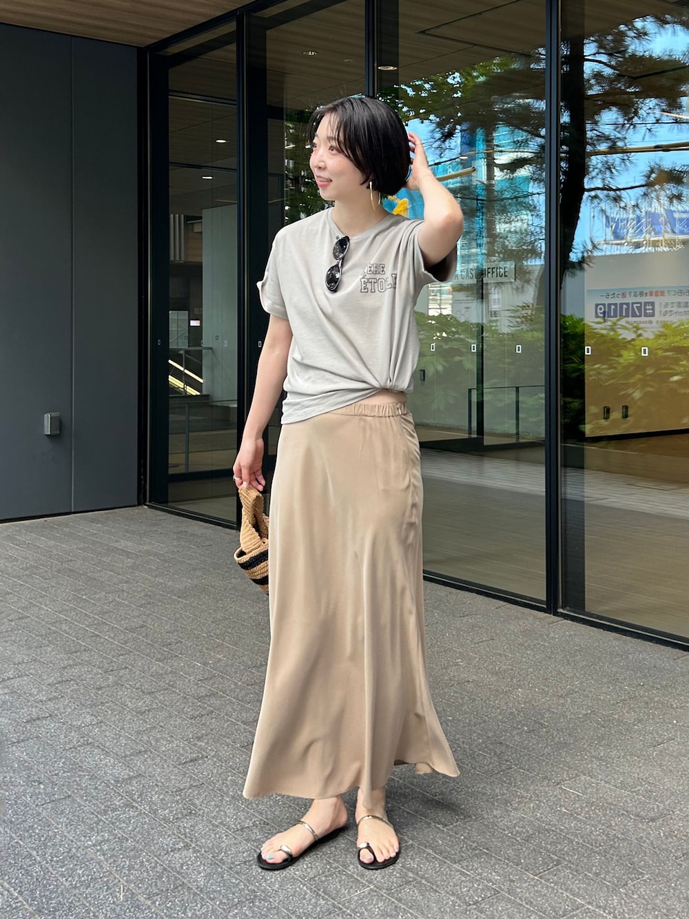 ベージュ系のスカート、グリーン系のTシャツ/カットソー、ブラック系のサンダルを着用したレディースの春コーディネートの1枚目の写真
