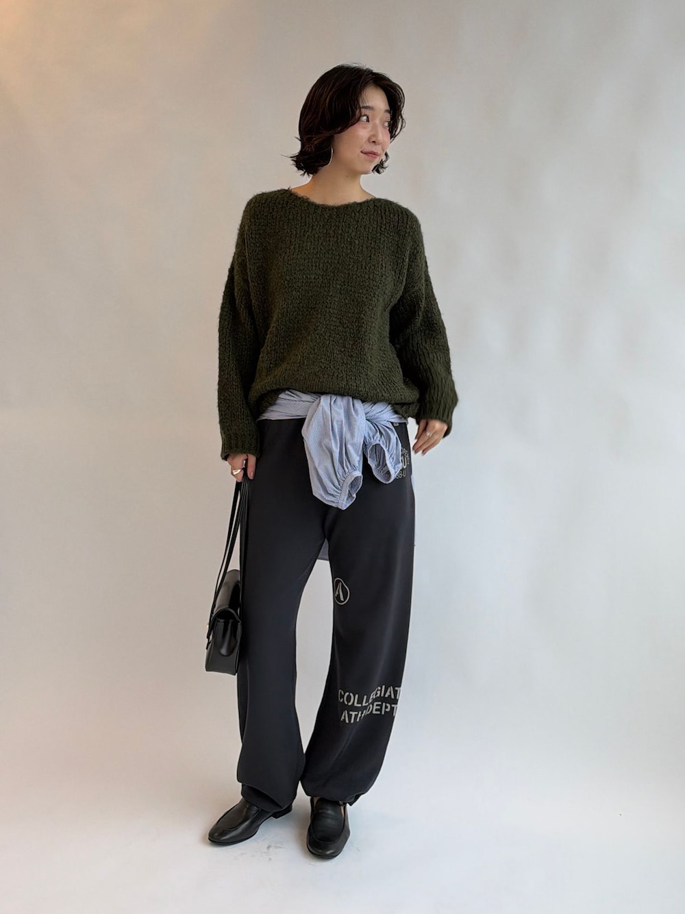 ブルー系のシャツ/ブラウス、グリーン系のニット/セーター、ブラック系のショルダーバッグを着用したレディースの秋コーディネートの1枚目の写真
