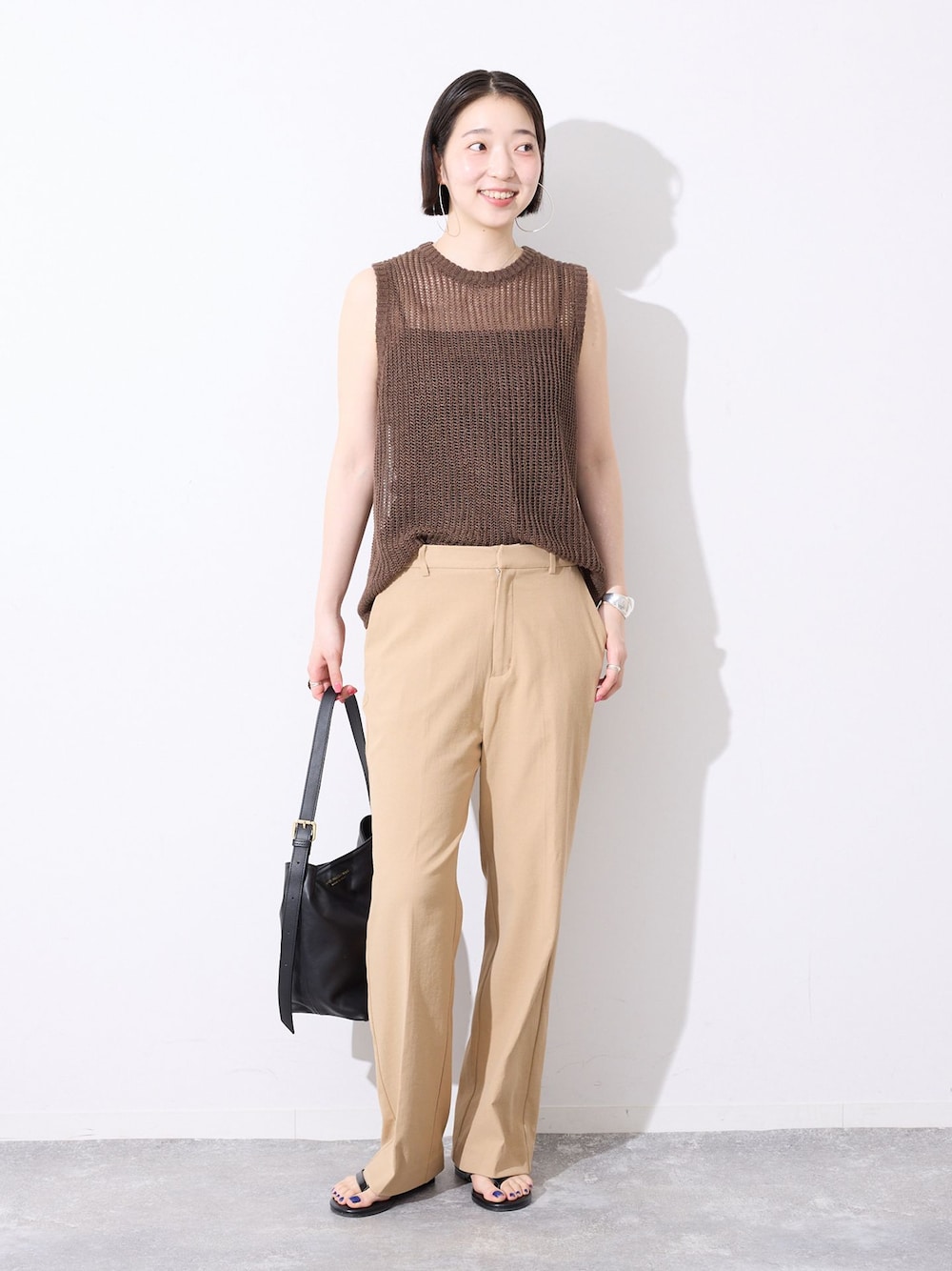 ベージュ系のその他パンツ、ブラウン系のニット/セーター、ブラック系のサンダルを着用したレディースの春コーディネートの1枚目の写真