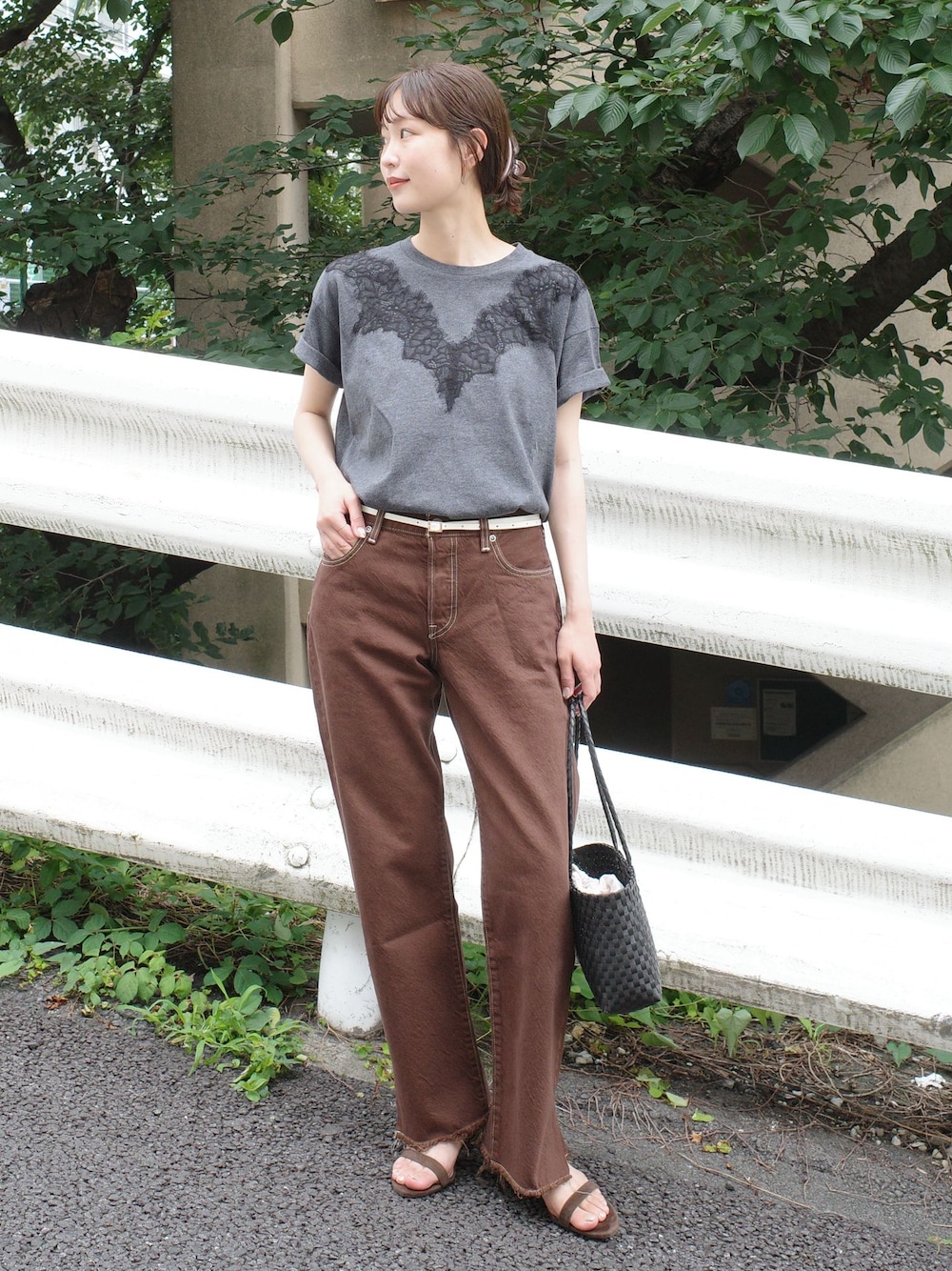 ブラウン系のデニムパンツ、グレー系のTシャツ/カットソー、ブラック系のかごバッグを着用したレディースの夏コーディネートの1枚目の写真