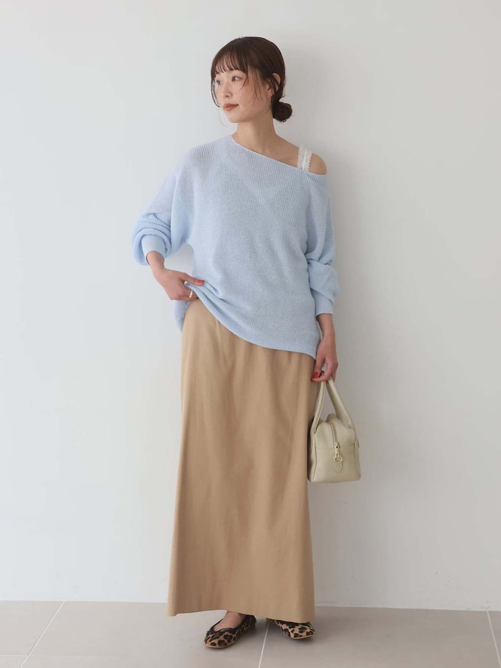 ベージュ系のバレエシューズ、ベージュ系のスカート、ブルー系のニット/セーターを着用したレディースの春コーディネートの1枚目の写真