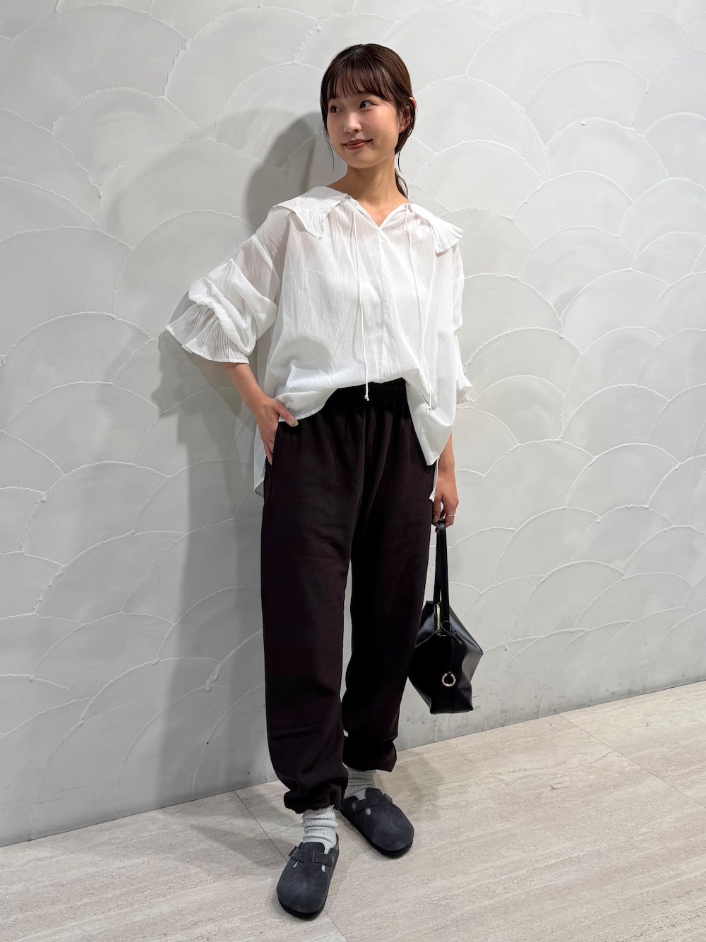 ブラウン系のスウェットパンツ、ホワイト系のシャツ/ブラウス、ブラック系のハンドバッグを着用したレディースの秋コーディネートの1枚目の写真