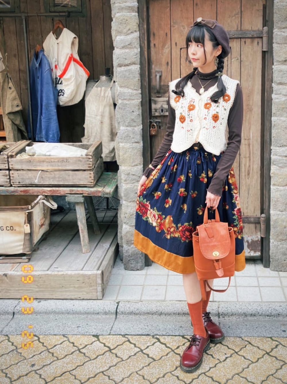 レッド系のブーツ、その他のスカート、ブラウン系のバッグを着用したレディースの秋コーディネートの1枚目の写真