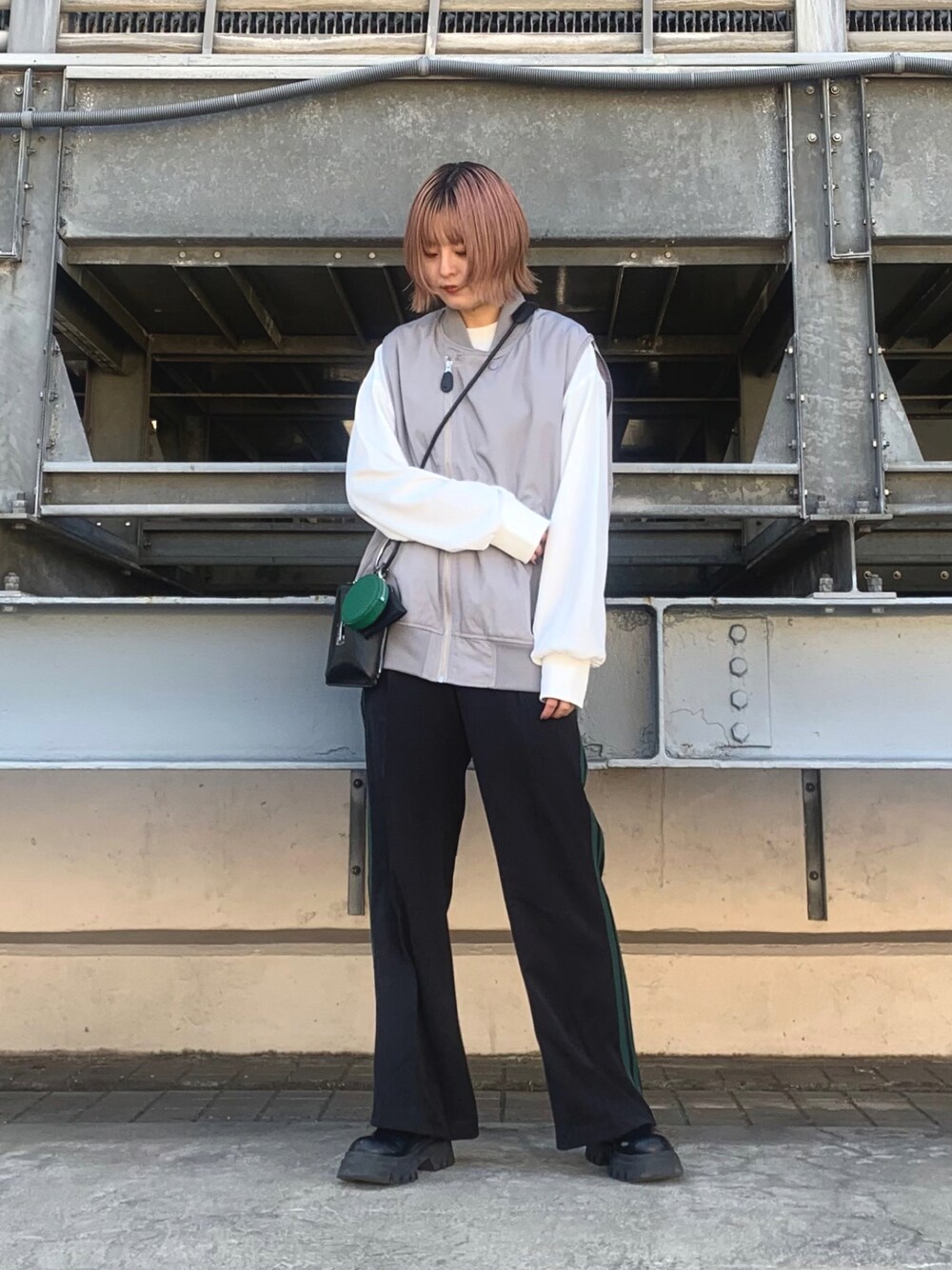 グレー系のベスト、ホワイト系のTシャツ/カットソー、ブラック系のショルダーバッグを着用したレディースの春コーディネートの1枚目の写真