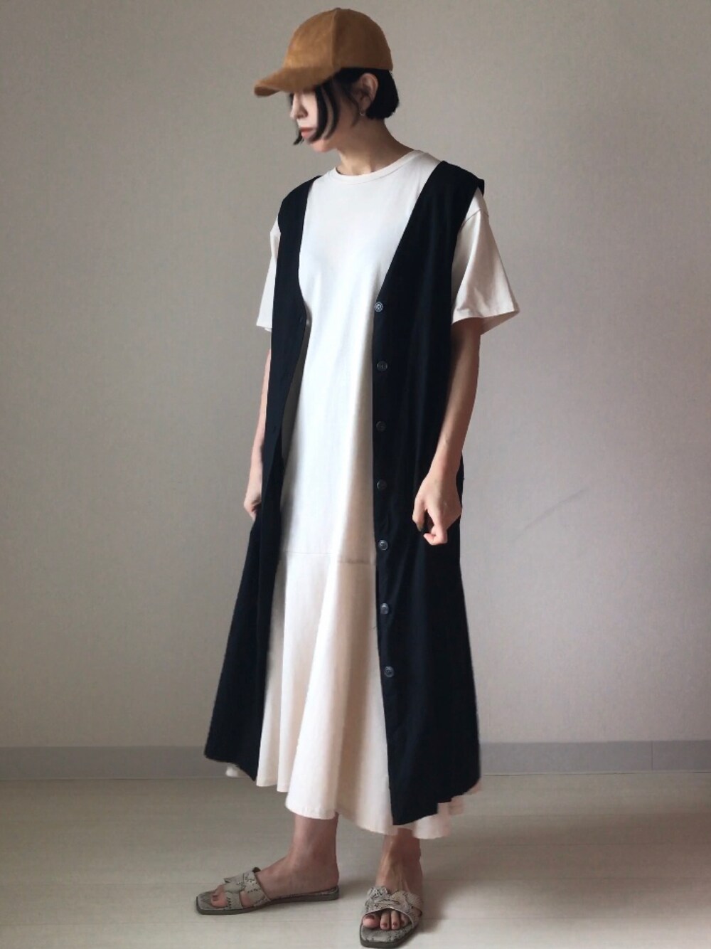 ホワイト系のワンピース、ブラック系のジャンパースカートを着用したレディースの夏コーディネートの1枚目の写真