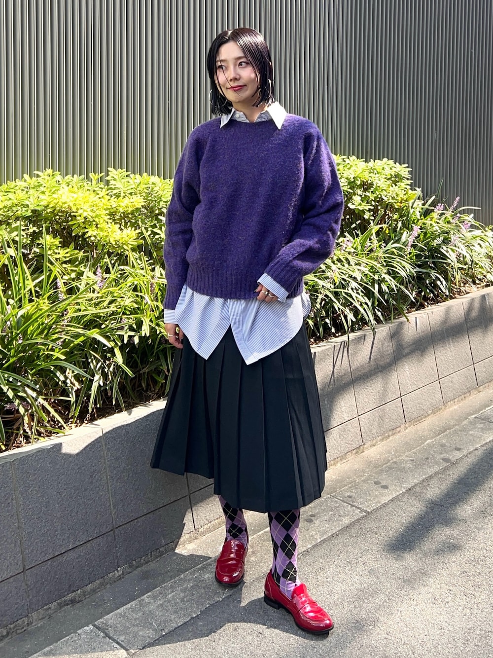 パープル系のニット/セーター、ブルー系のシャツ/ブラウス、ブラック系のスカートを着用したレディースの秋コーディネートの1枚目の写真