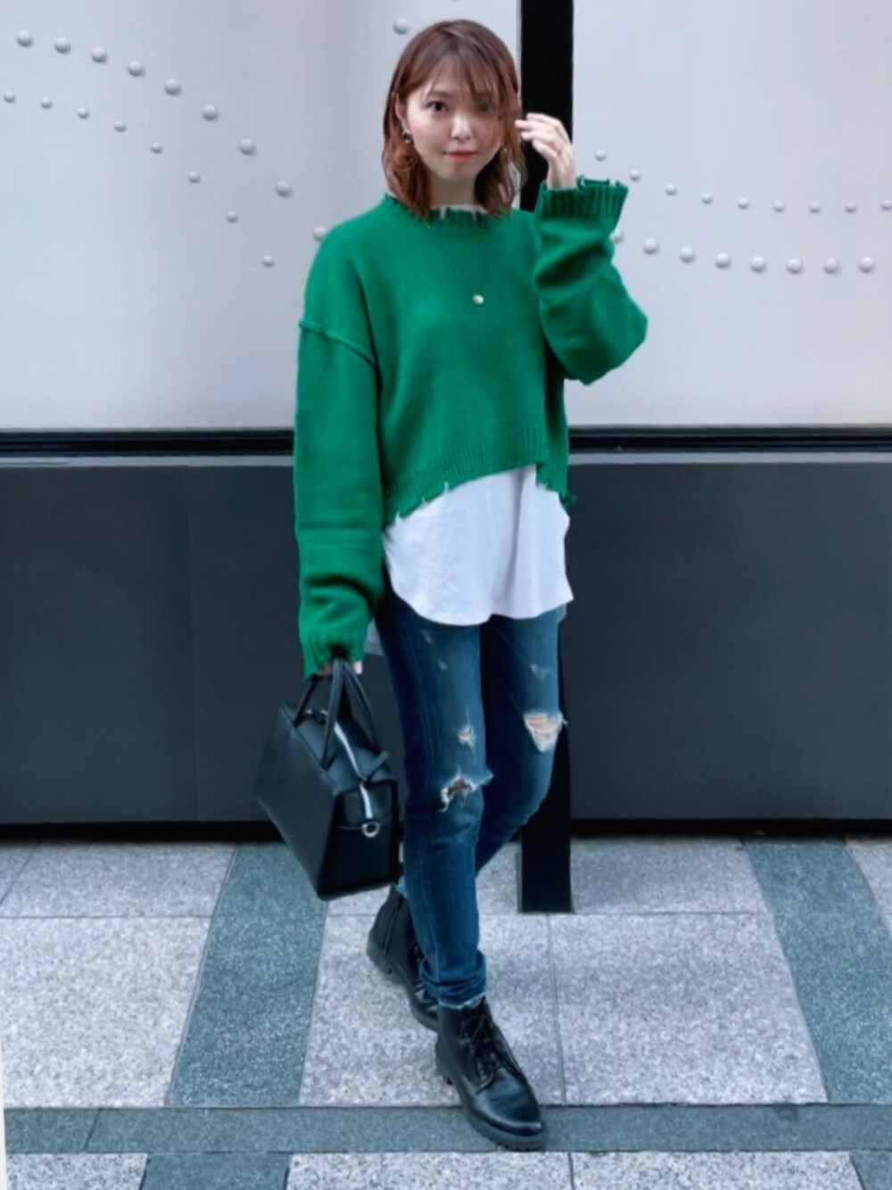 グリーン系のニット/セーター、ホワイト系のTシャツ/カットソー、ブルー系のデニムパンツを着用したレディースの秋コーディネートの1枚目の写真