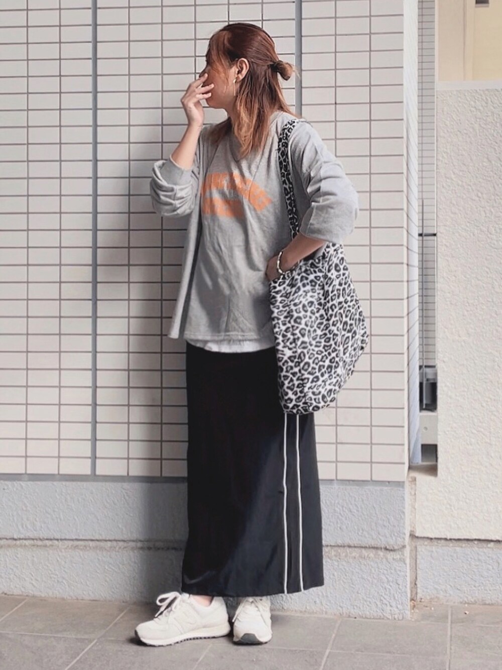 グレー系のTシャツ/カットソー、ブラック系のスカート、ホワイト系のスニーカーを着用したレディースの秋コーディネートの1枚目の写真