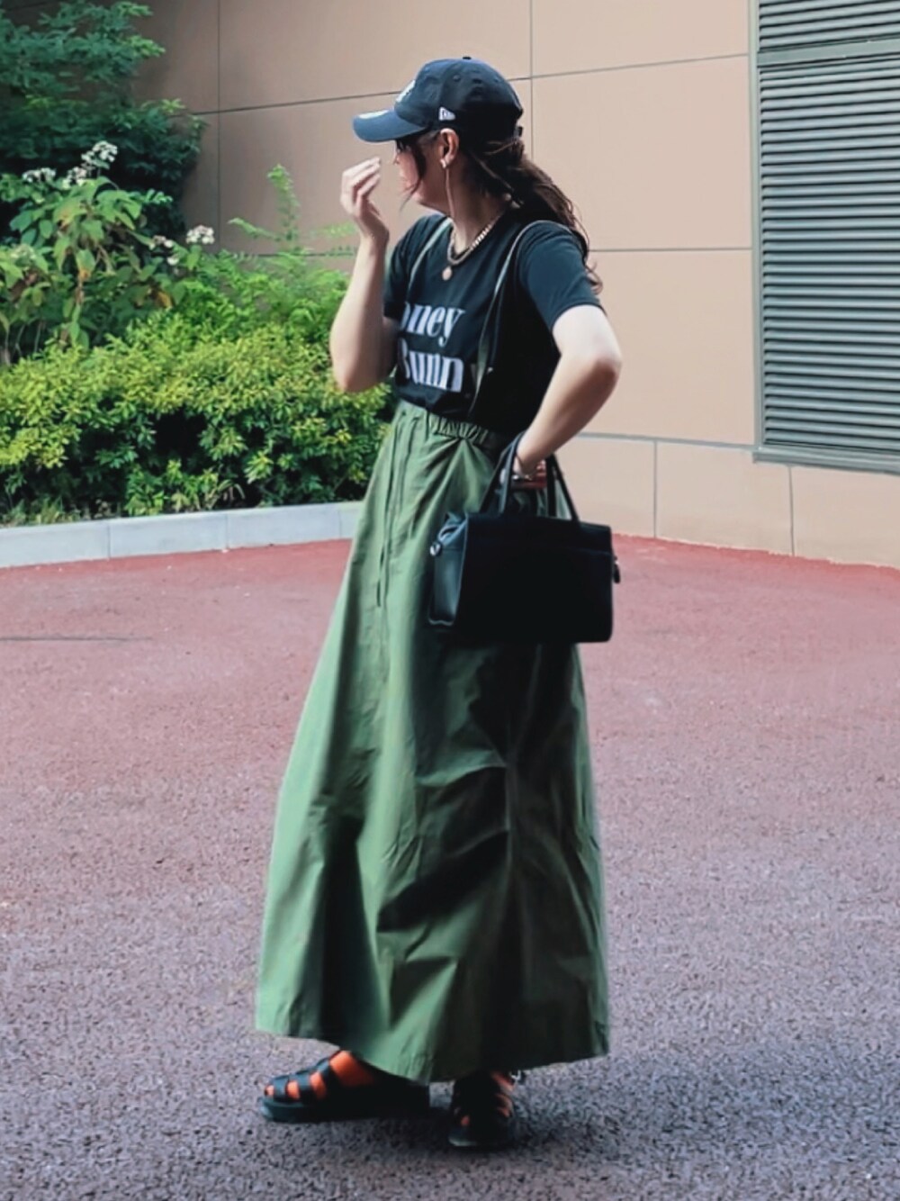 ブラック系のTシャツ/カットソー、グリーン系のスカート、ブラック系のサンダルを着用したレディースの夏コーディネートの1枚目の写真