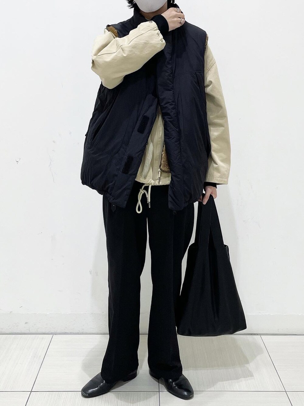 ブラック系のダウンベスト、ブラック系のスラックス、ブラック系のトートバッグを着用したメンズの秋コーディネートの1枚目の写真