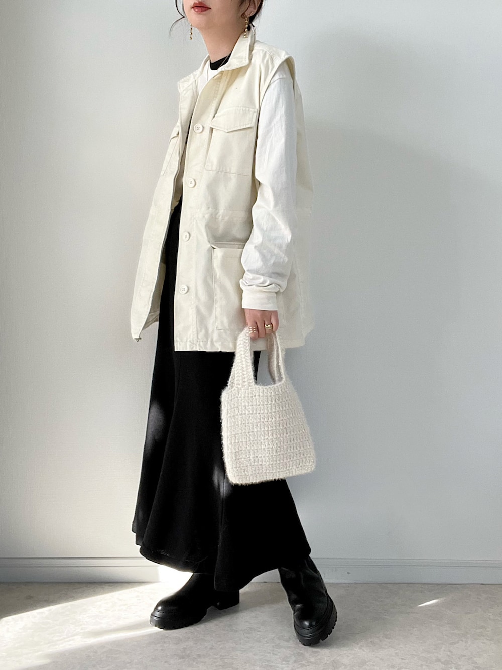 ホワイト系のベスト、ブラック系のスカート、ホワイト系のトートバッグを着用したレディースの冬コーディネートの1枚目の写真