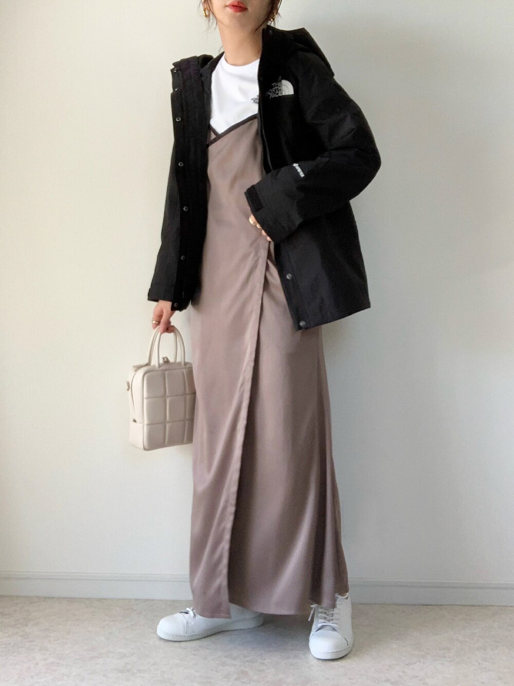 ブラック系のナイロンジャケット、グレー系のワンピース、ホワイト系のスニーカーを着用したレディースの春コーディネートの1枚目の写真