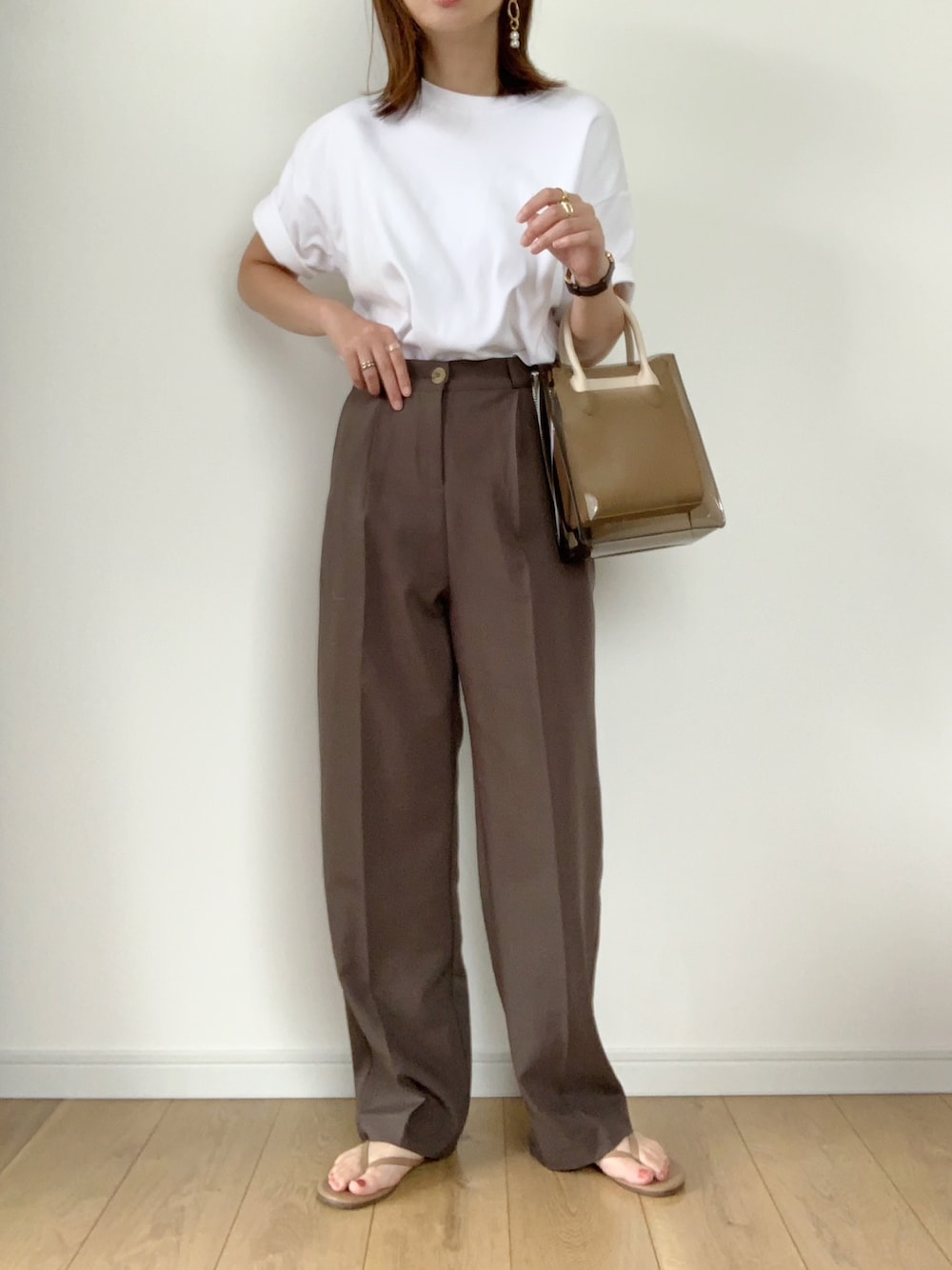ホワイト系のTシャツ/カットソー、ブラウン系のスラックス、ベージュ系のサンダルを着用したレディースの夏コーディネートの1枚目の写真
