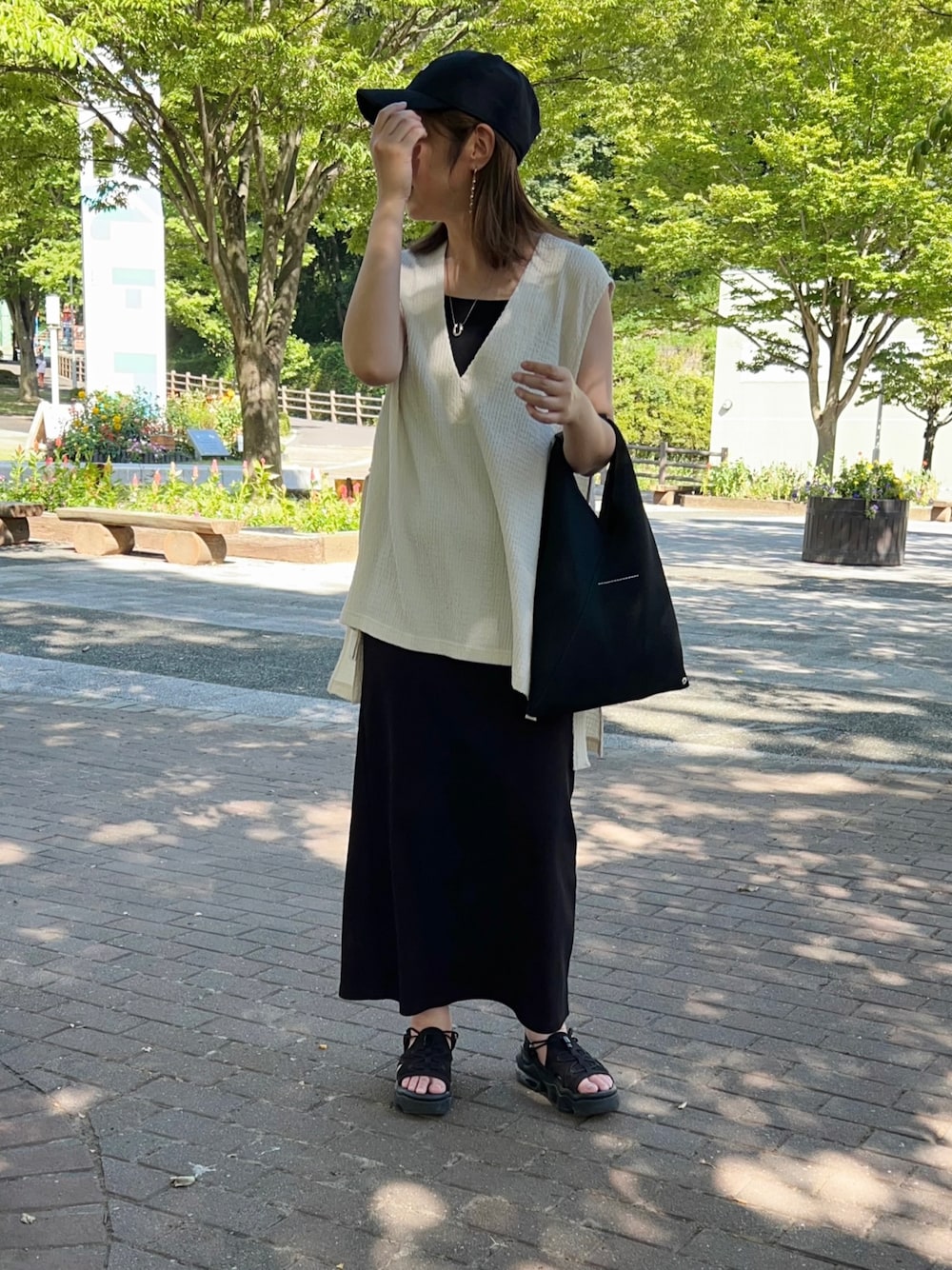 ブラック系のワンピース、ホワイト系のベスト、ブラック系のトートバッグを着用したレディースの夏コーディネートの1枚目の写真