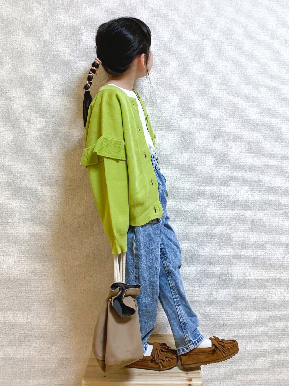 イエロー系のニット/セーター、ホワイト系のTシャツ/カットソー、ブルー系のデニムパンツを着用したキッズの冬コーディネートの1枚目の写真