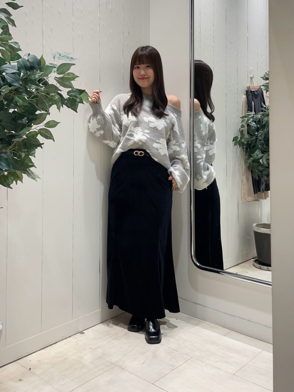 グレー系のニット/セーター、ブラック系のスカート、ブラック系のブーツを着用したレディースの秋コーディネートの1枚目の写真