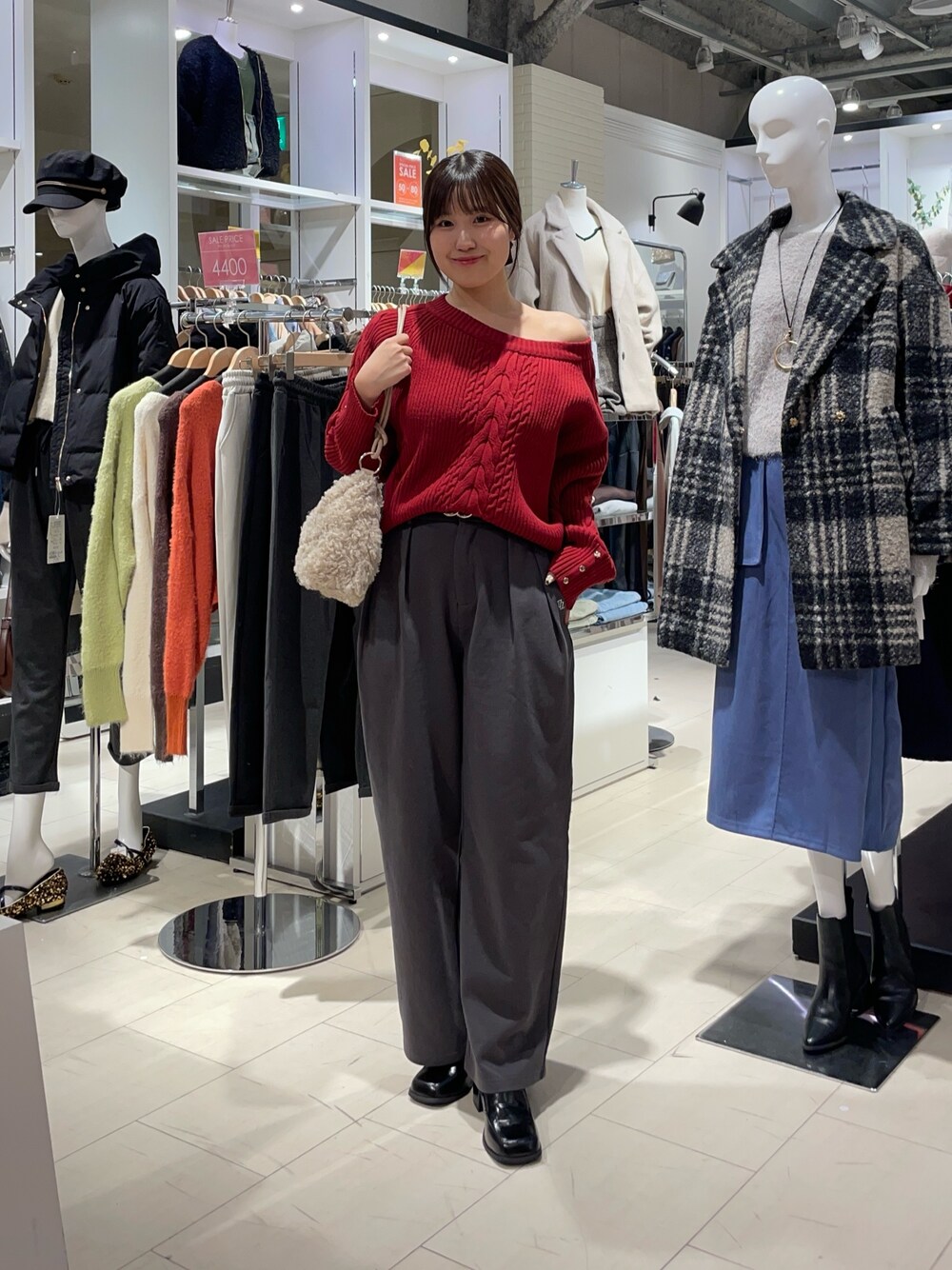 レッド系のニット/セーター、グレー系のその他パンツ、ブラック系のブーツを着用したレディースの秋コーディネートの1枚目の写真
