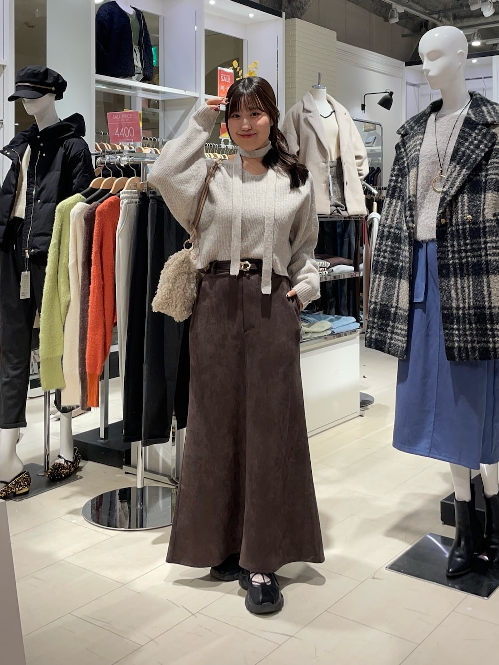 ベージュ系のニット/セーター、ブラウン系のスカート、ベージュ系のトートバッグを着用したレディースの秋コーディネートの1枚目の写真