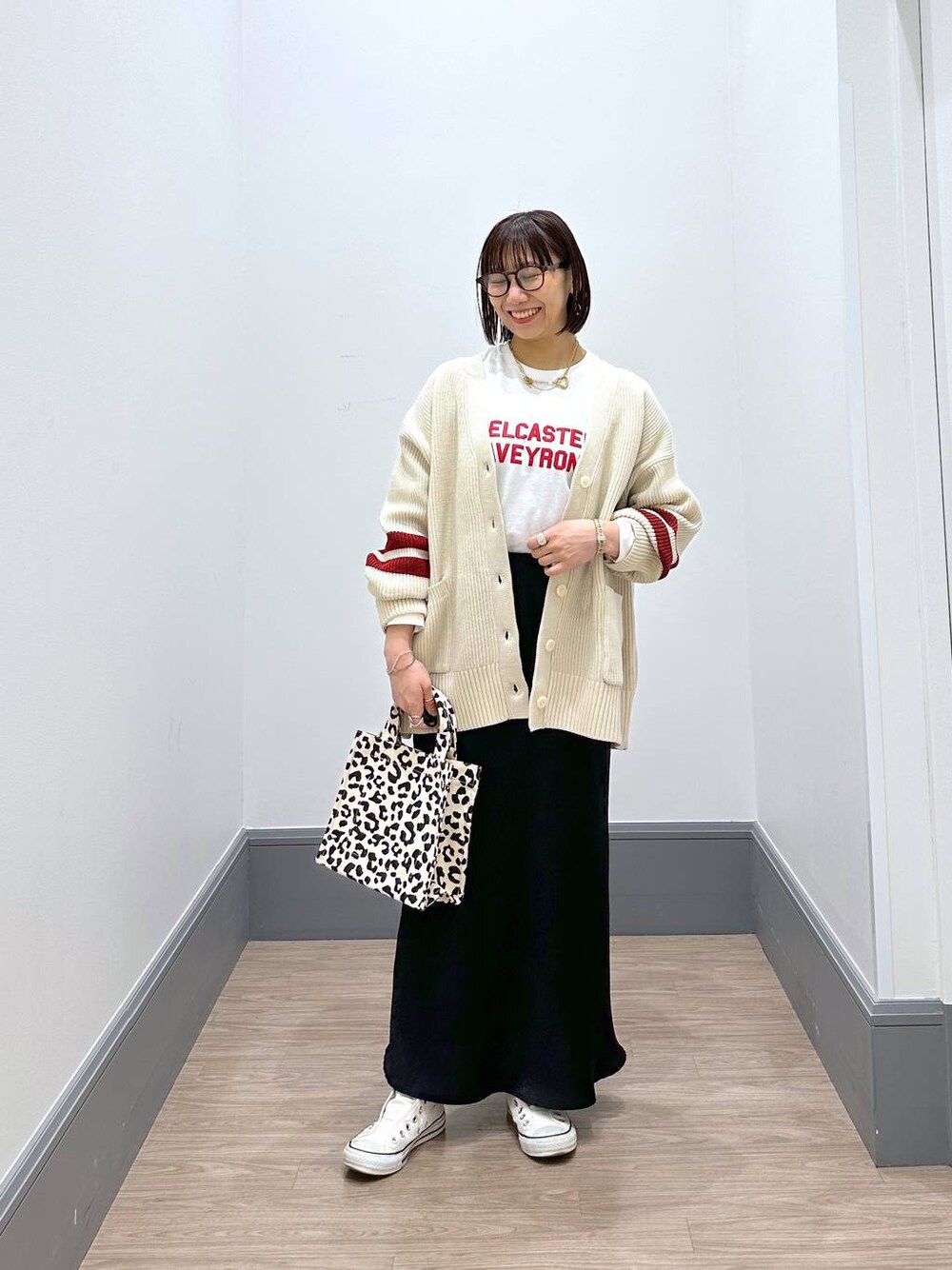 ホワイト系のニット/セーター、ホワイト系のTシャツ/カットソー、ブラック系のスカートを着用したレディースの冬コーディネートの1枚目の写真