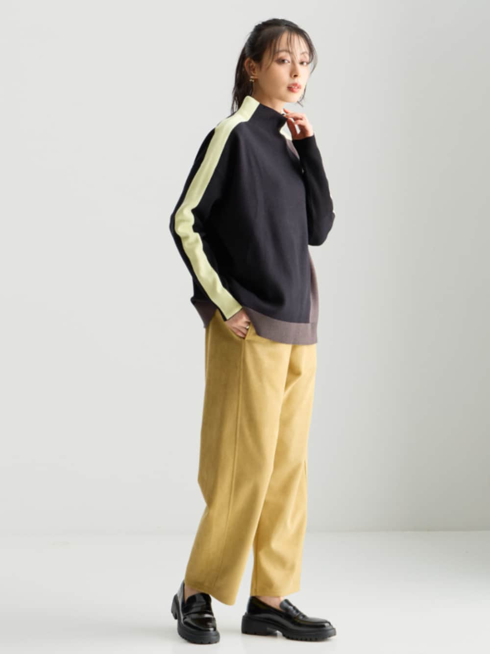 ブラック系のニット/セーター、イエロー系のパンツを着用したレディースの秋コーディネートの1枚目の写真