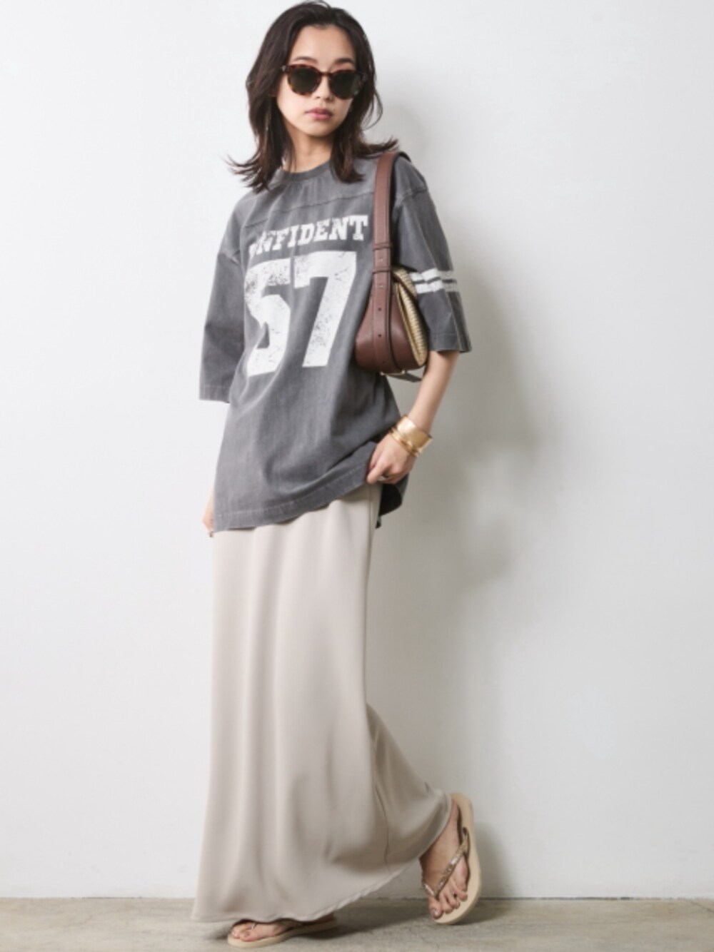 グレー系のTシャツ/カットソー、ベージュ系のスカートを着用したレディースの春コーディネートの1枚目の写真