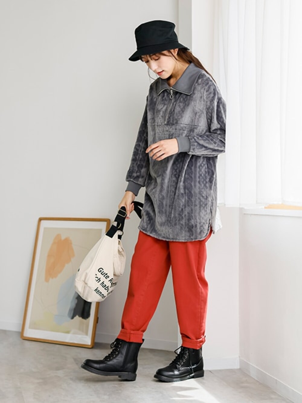 レッド系のデニムパンツ、グレー系のチュニック、ブラック系のブーツを着用したレディースの秋コーディネートの1枚目の写真