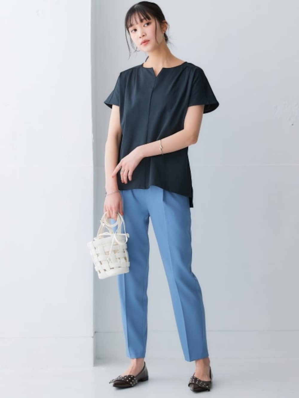 ブルー系のスラックス、ブラック系のTシャツ/カットソーを着用したレディースの春コーディネートの1枚目の写真