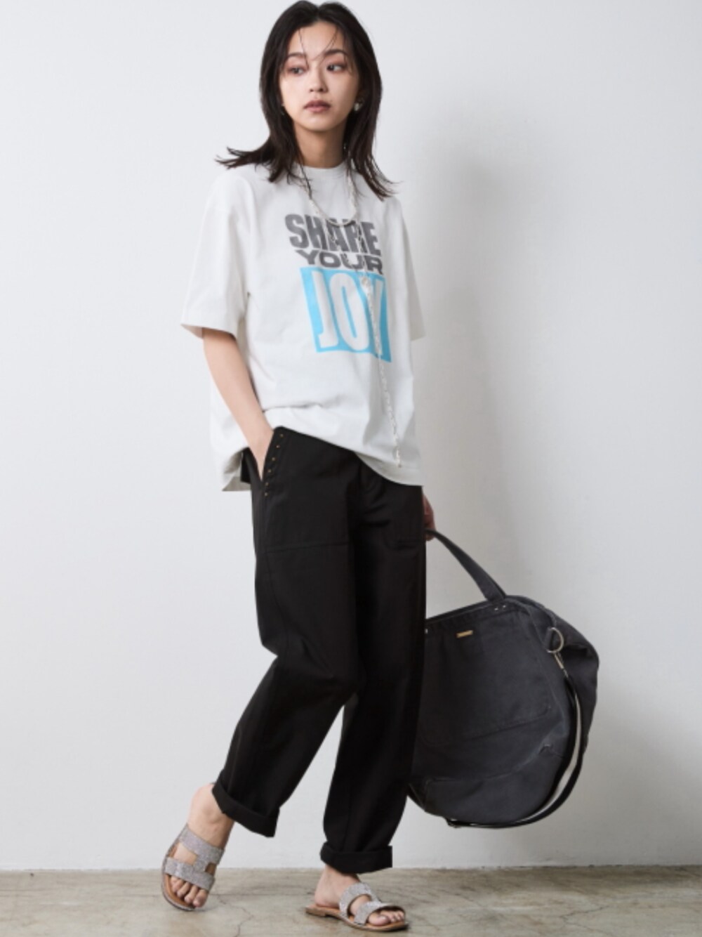 ブラック系のその他パンツ、ホワイト系のTシャツ/カットソー、グレー系のトートバッグを着用したレディースの春コーディネートの1枚目の写真