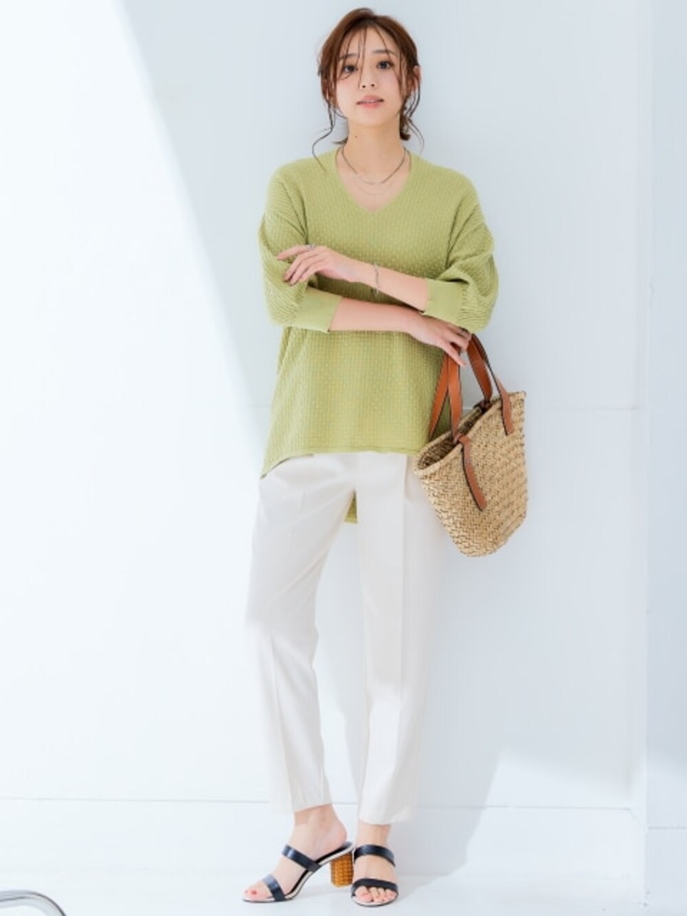 ベージュ系のスラックス、グリーン系のニット/セーターを着用したレディースの春コーディネートの1枚目の写真