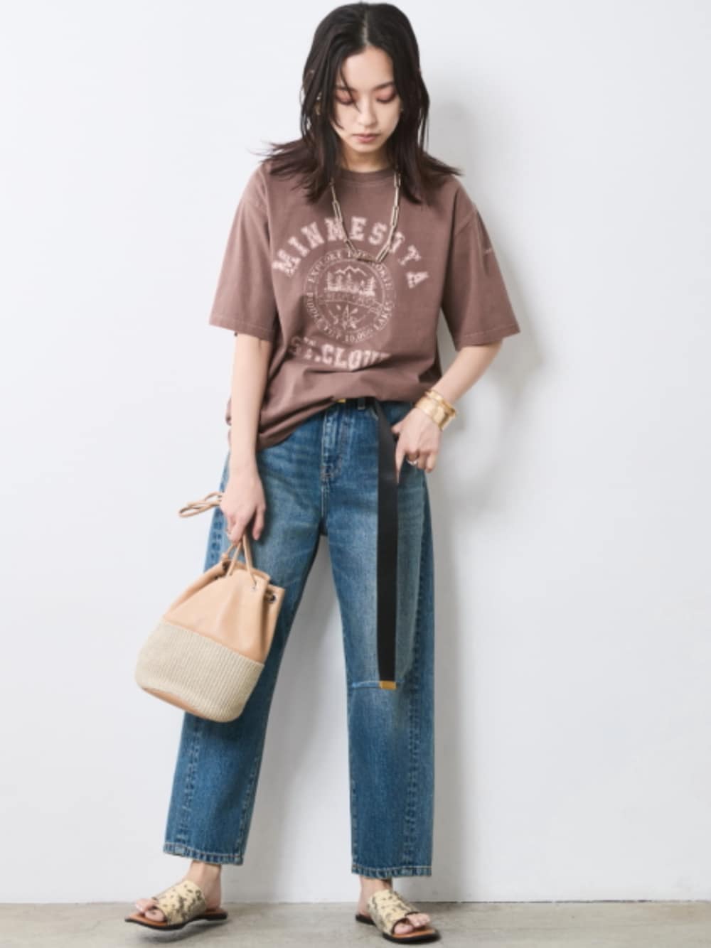 ブルー系のデニムパンツ、ブラウン系のTシャツ/カットソー、ブラック系のベルトを着用したレディースの春コーディネートの1枚目の写真