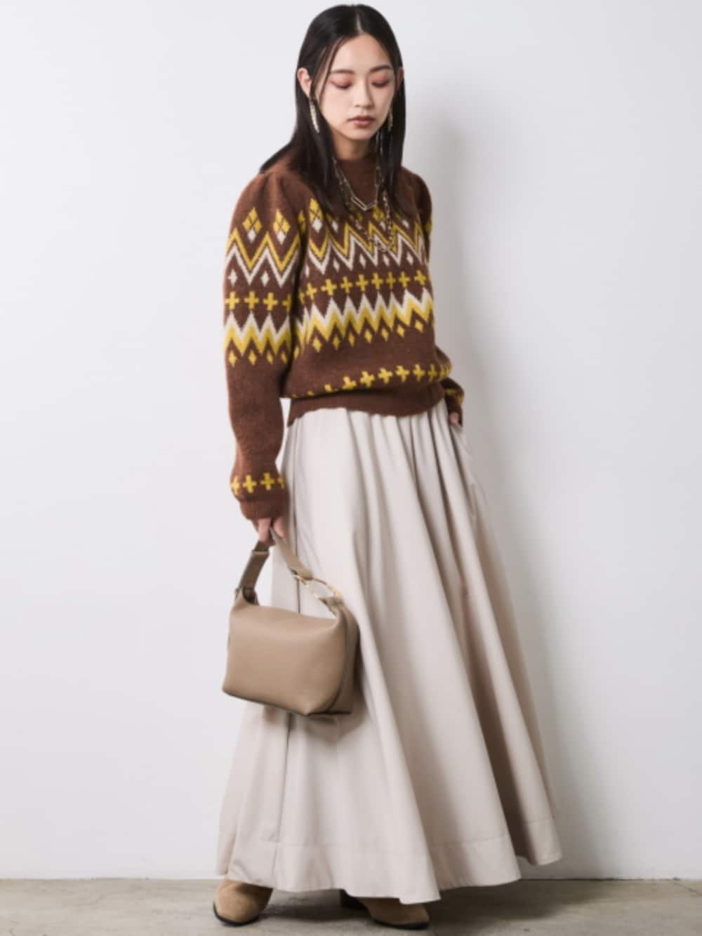 ブラウン系のニット/セーター、ベージュ系のスカートを着用したレディースの秋コーディネートの1枚目の写真
