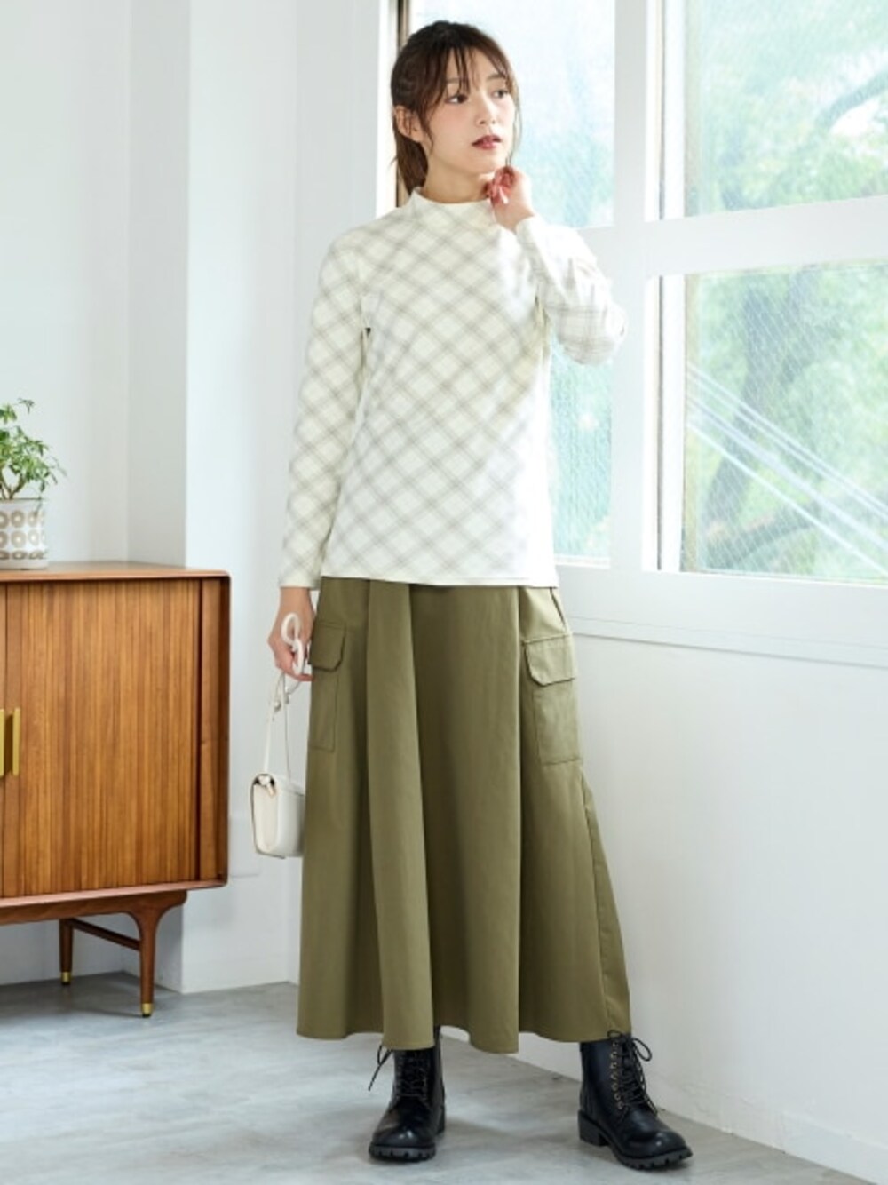 グリーン系のスカート、ホワイト系のTシャツ/カットソー、ブラック系のブーツを着用したレディースの秋コーディネートの1枚目の写真