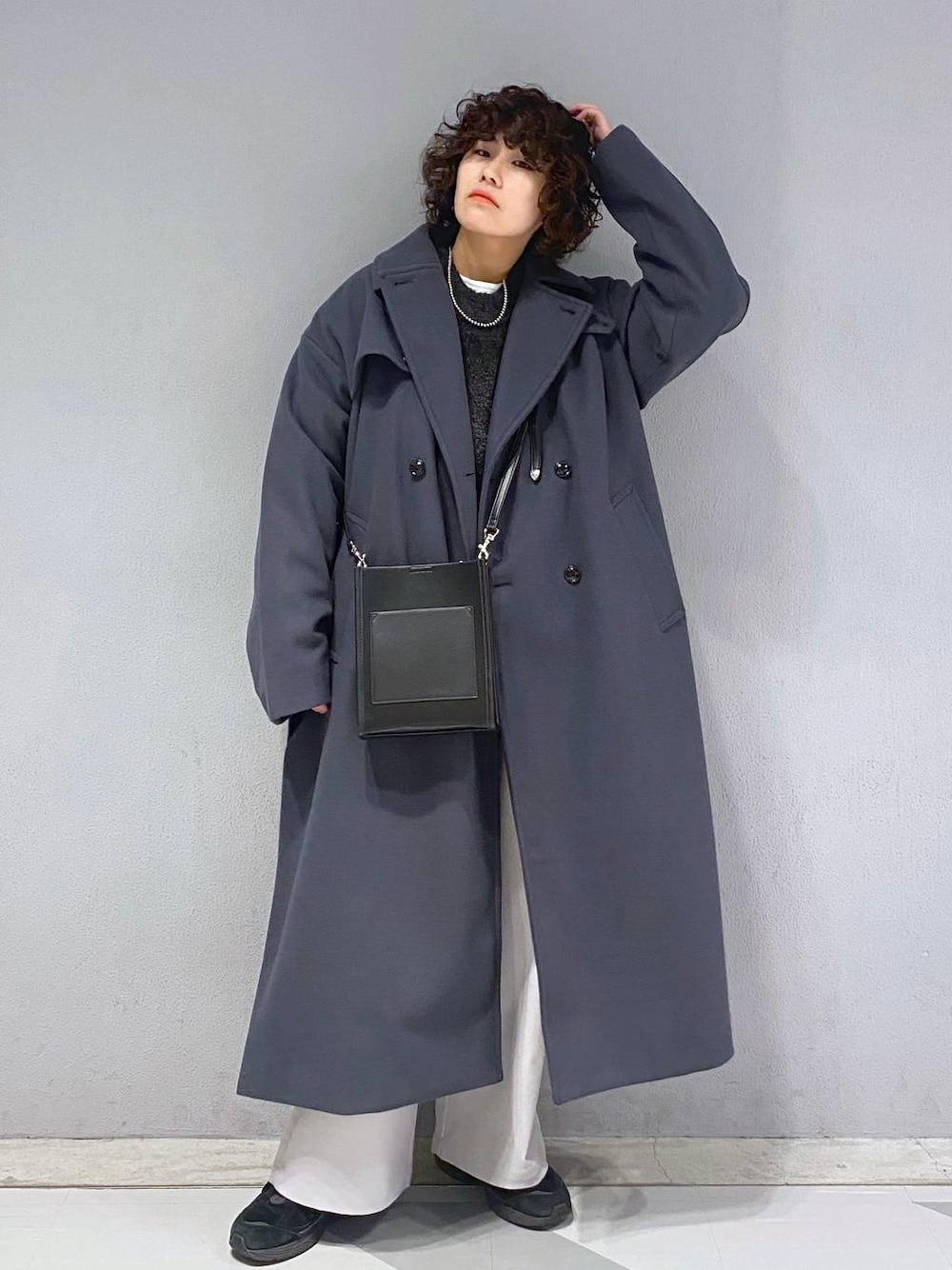 グレー系のトレンチコート、ブラック系のニット/セーター、ブラック系のショルダーバッグを着用したメンズの冬コーディネートの1枚目の写真