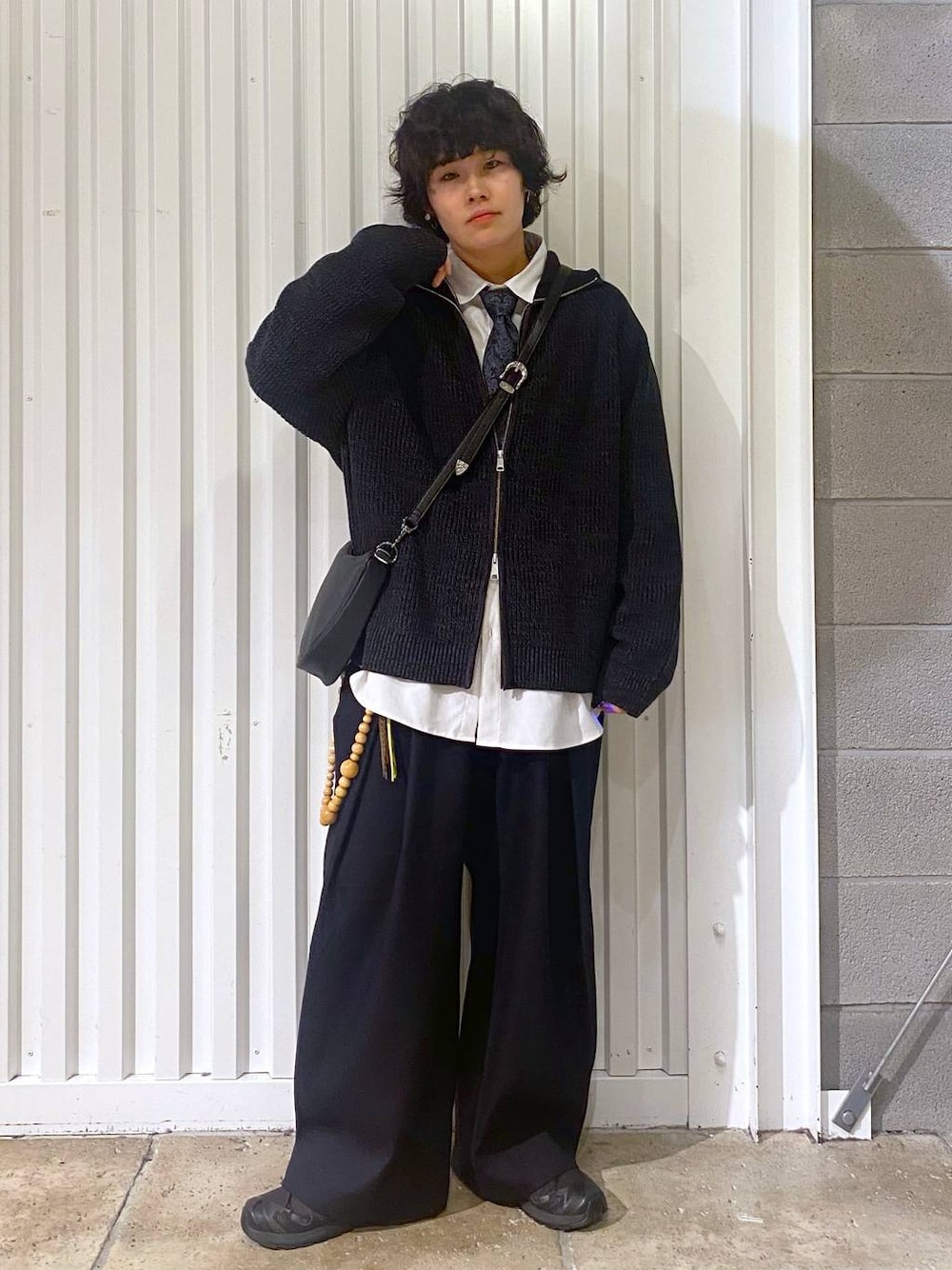 ブラック系のスニーカー、ブラック系のニット/セーター、ブラック系のショルダーバッグを着用したメンズの秋コーディネートの1枚目の写真