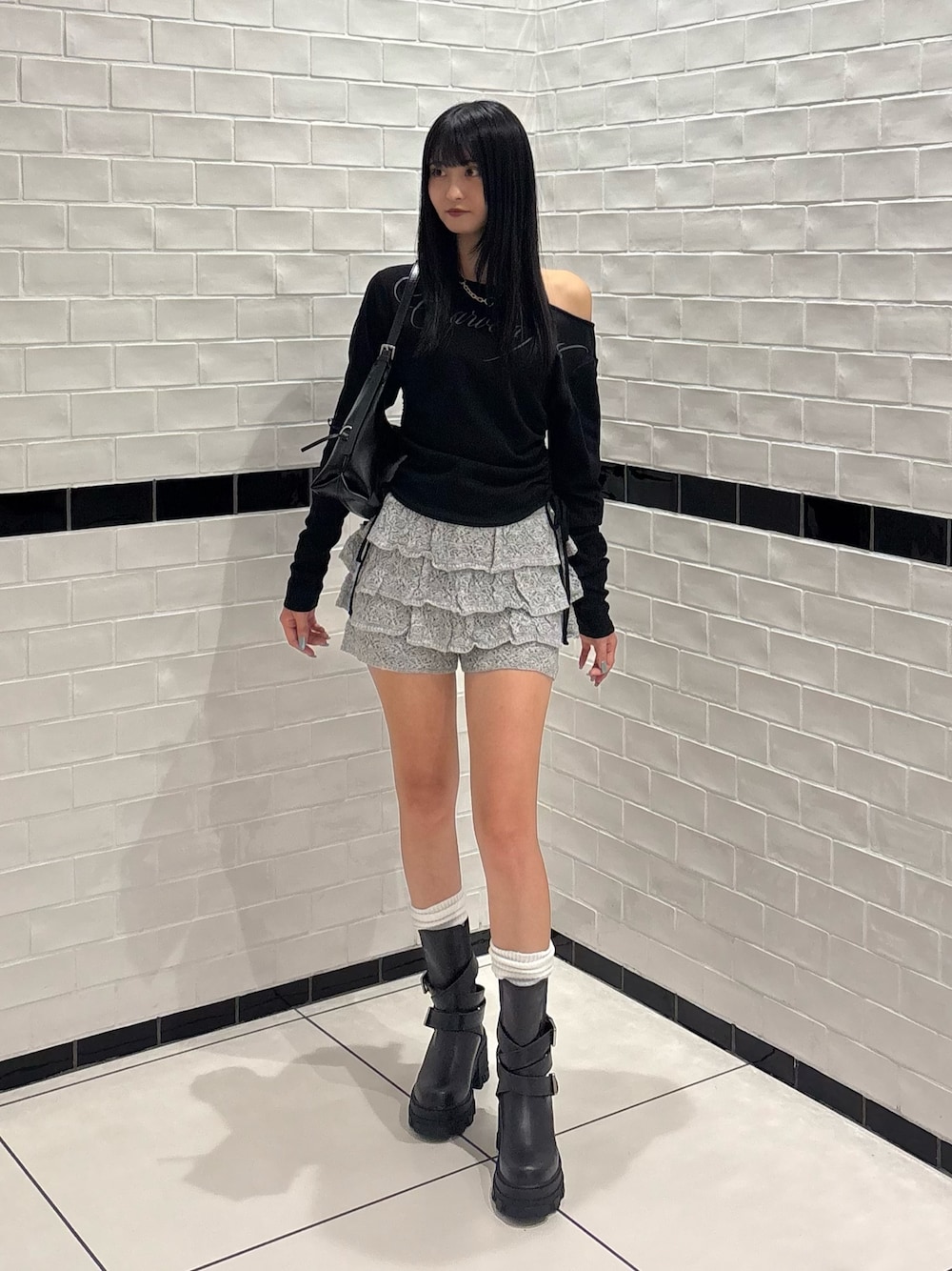 ブラック系のブーツ、グレー系のスカート、ブラック系のTシャツ/カットソーを着用したレディースの秋コーディネートの1枚目の写真