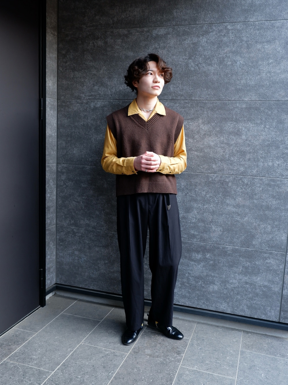 ブラック系のスリッポン、ブラウン系のベスト、イエロー系のシャツ/ブラウスを着用したメンズの春コーディネートの1枚目の写真