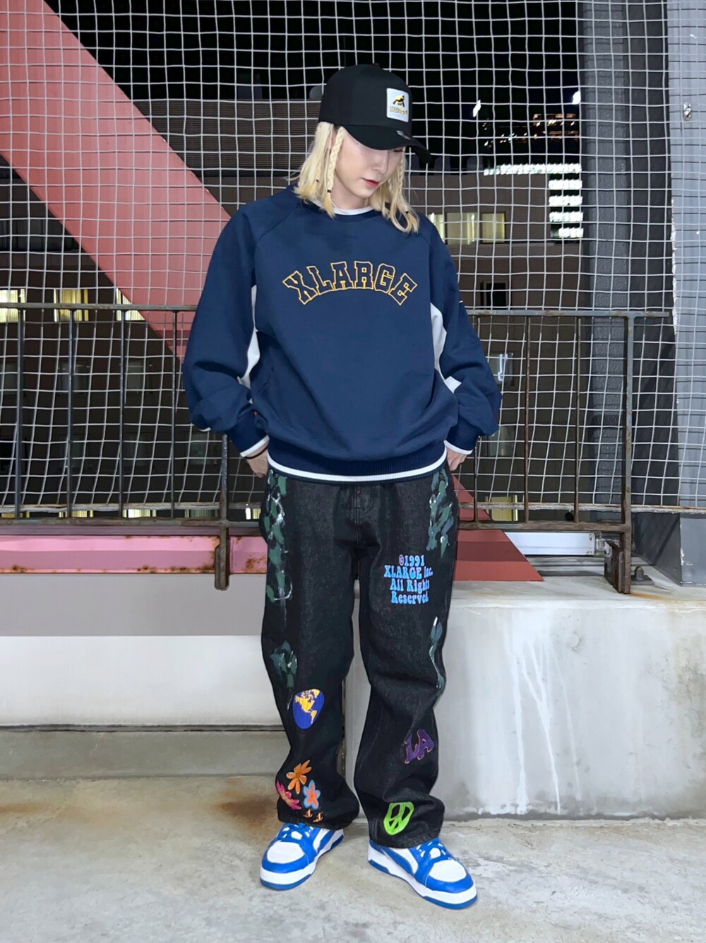 ブルー系のスウェット、ブルー系のデニムパンツ、ブラック系のキャップを着用したレディースの冬コーディネートの1枚目の写真