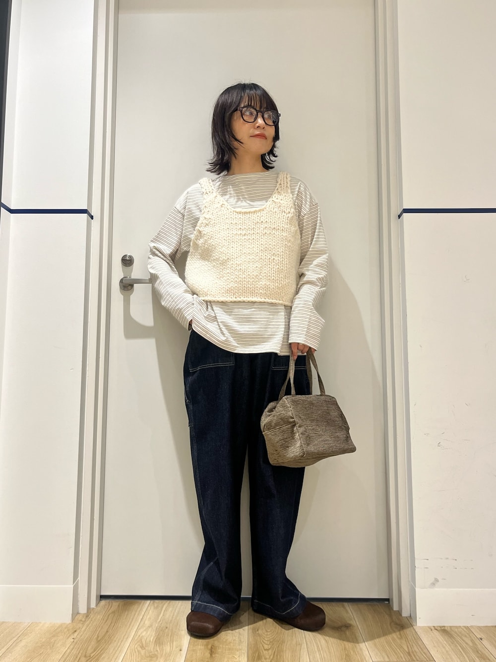 ブルー系のデニムパンツ、グリーン系のハンドバッグ、ホワイト系のTシャツ/カットソーを着用したレディースの秋コーディネートの1枚目の写真