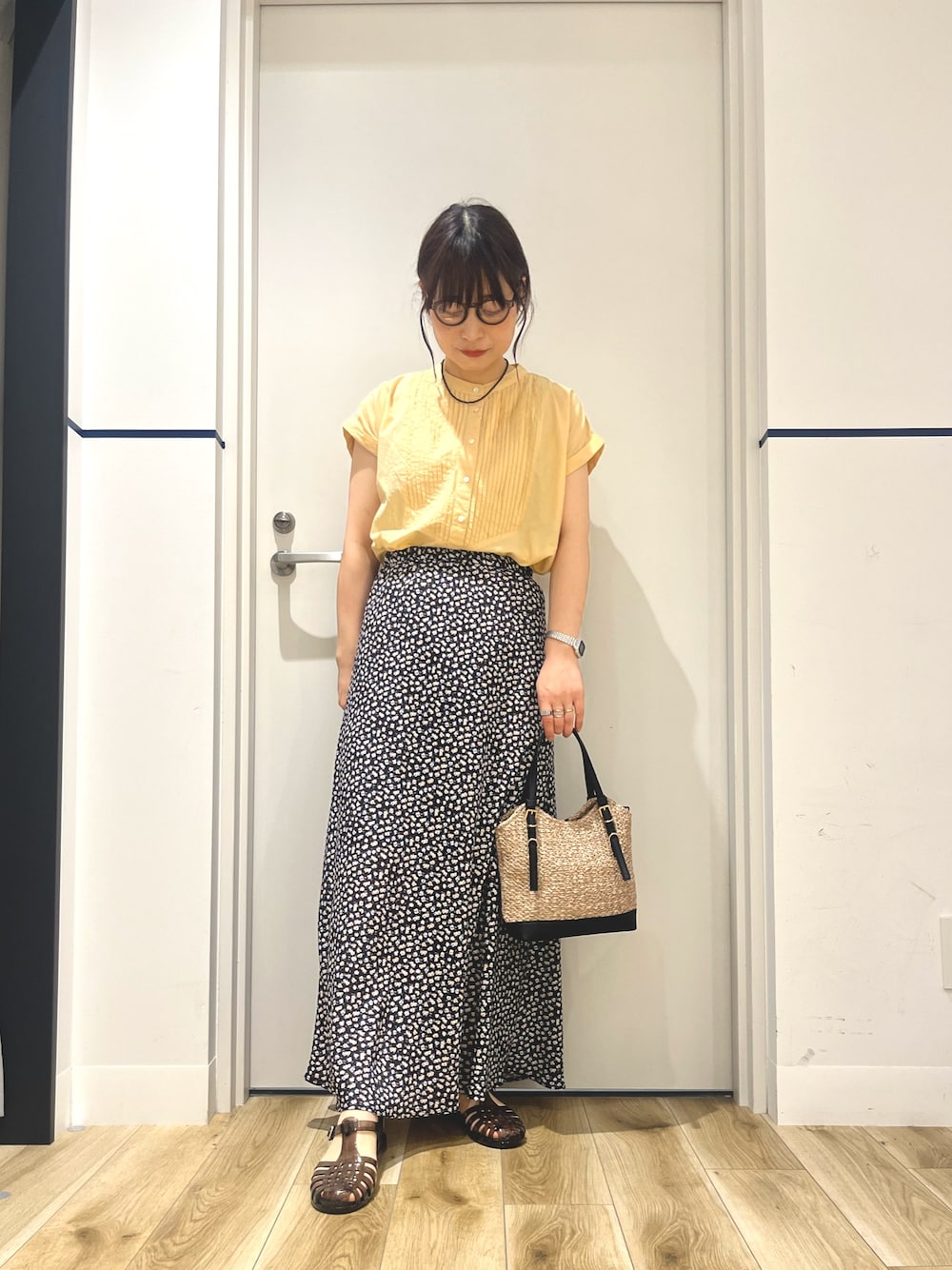 イエロー系のシャツ/ブラウス、ホワイト系のスカート、ブラック系のショルダーバッグを着用したレディースの夏コーディネートの1枚目の写真