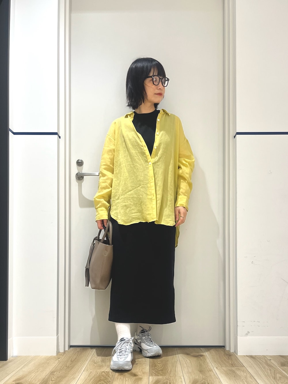 イエロー系のシャツ/ブラウス、ブラック系のワンピース、グレー系のスニーカーを着用したレディースの夏コーディネートの1枚目の写真