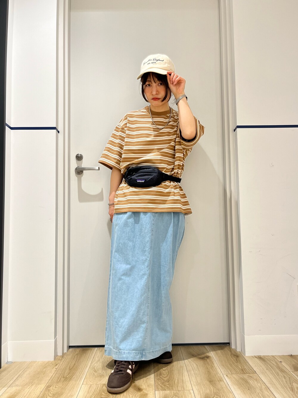 ブラック系のボディバッグ/ウエストポーチ、ブラウン系のTシャツ/カットソー、ブルー系のスカートを着用したレディースの春コーディネートの1枚目の写真