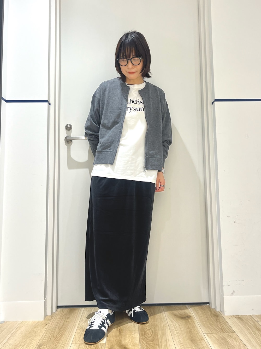 ブラック系のスニーカー、ブラック系のスカート、ホワイト系のTシャツ/カットソーを着用したレディースの秋コーディネートの1枚目の写真