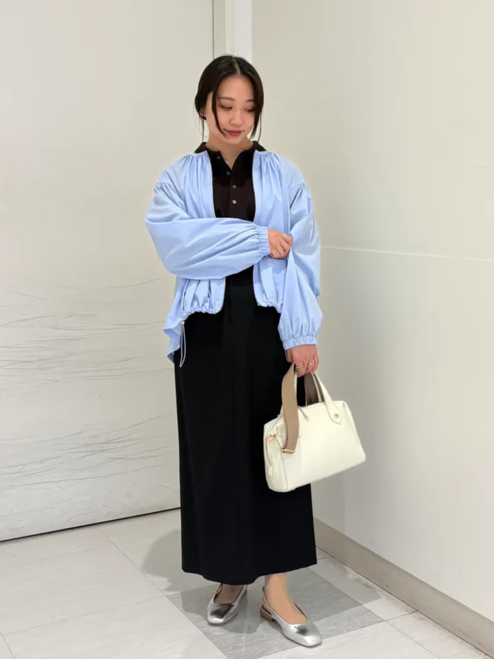 ベージュ系のボストンバッグ、シルバー系のパンプス、ブルー系のブルゾンを着用したレディースの春コーディネートの1枚目の写真