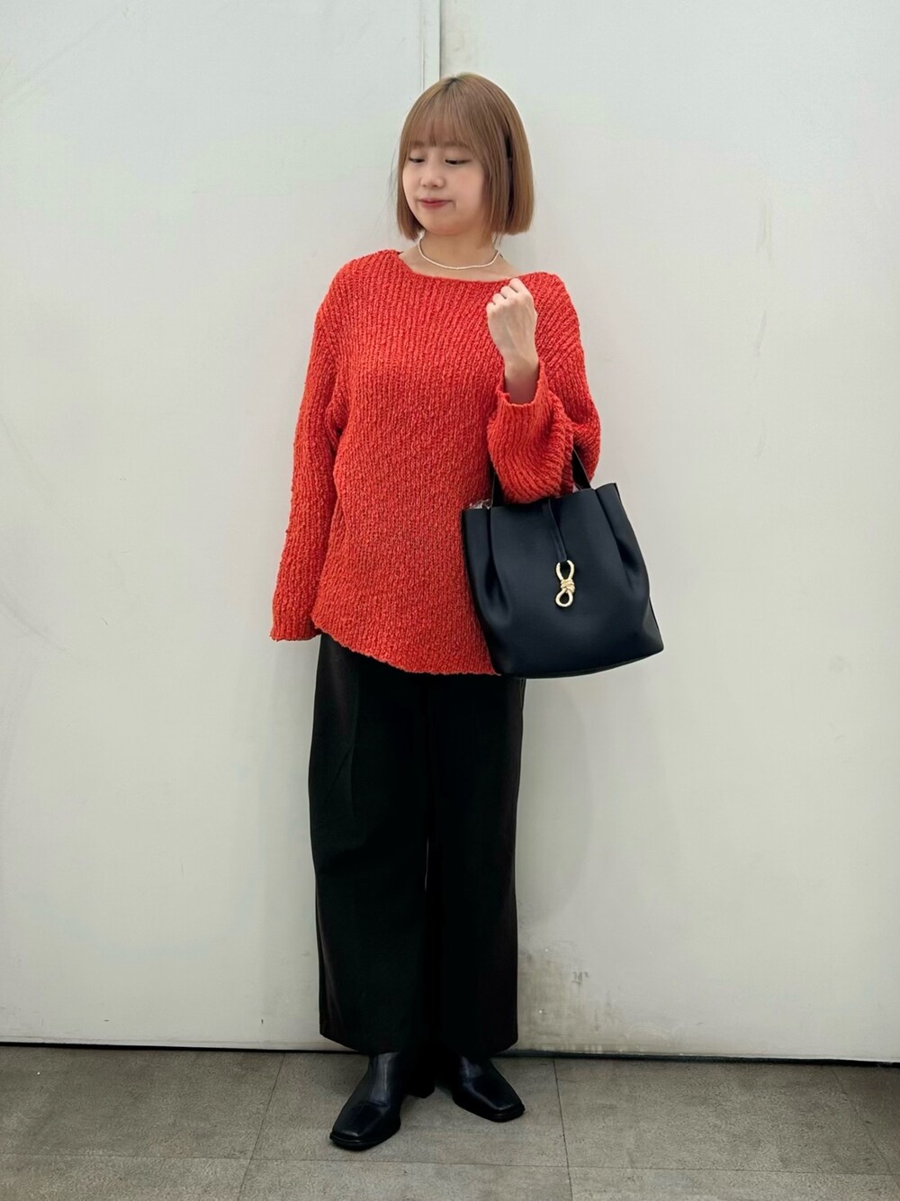 レッド系のニット/セーター、ブラウン系のその他パンツ、ブラック系のブーツを着用したレディースの秋コーディネートの1枚目の写真