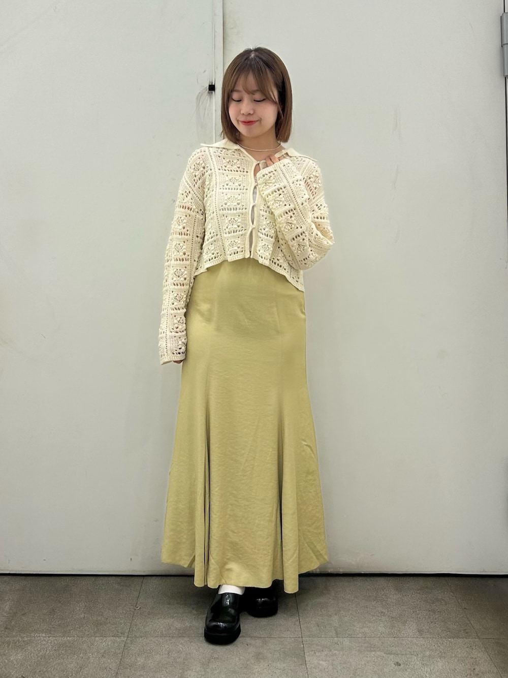 ホワイト系のカーディガン/ボレロ、ベージュ系のスカート、ブラック系のサンダルを着用したレディースの春コーディネートの1枚目の写真