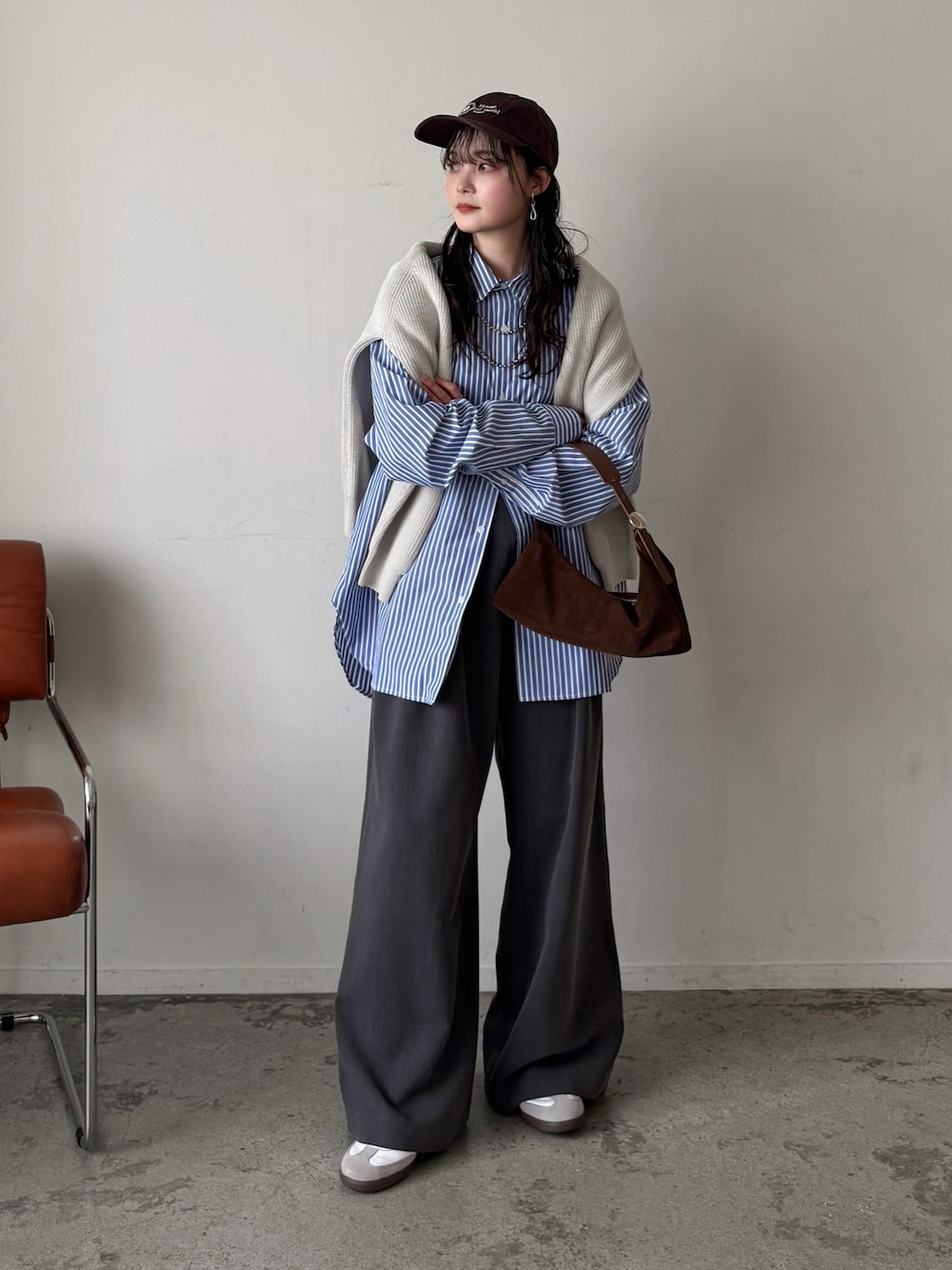 ブルー系のシャツ/ブラウス、ホワイト系のニット/セーター、グレー系のスラックスを着用したレディースの春コーディネートの1枚目の写真